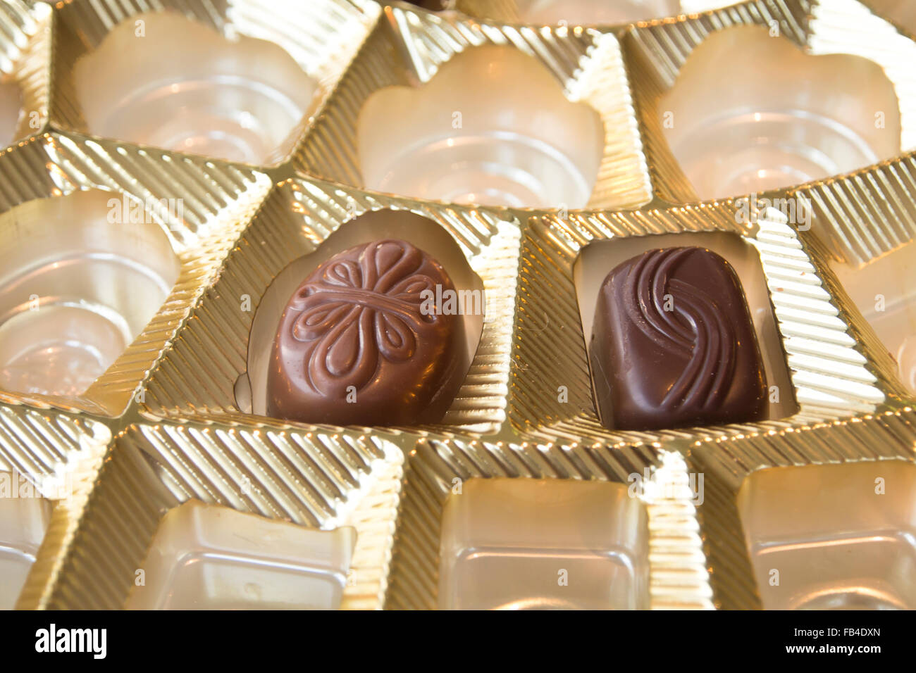 Zart und verführerisch Einzelstücke von Schokolade in goldene Schachtel Stockfoto