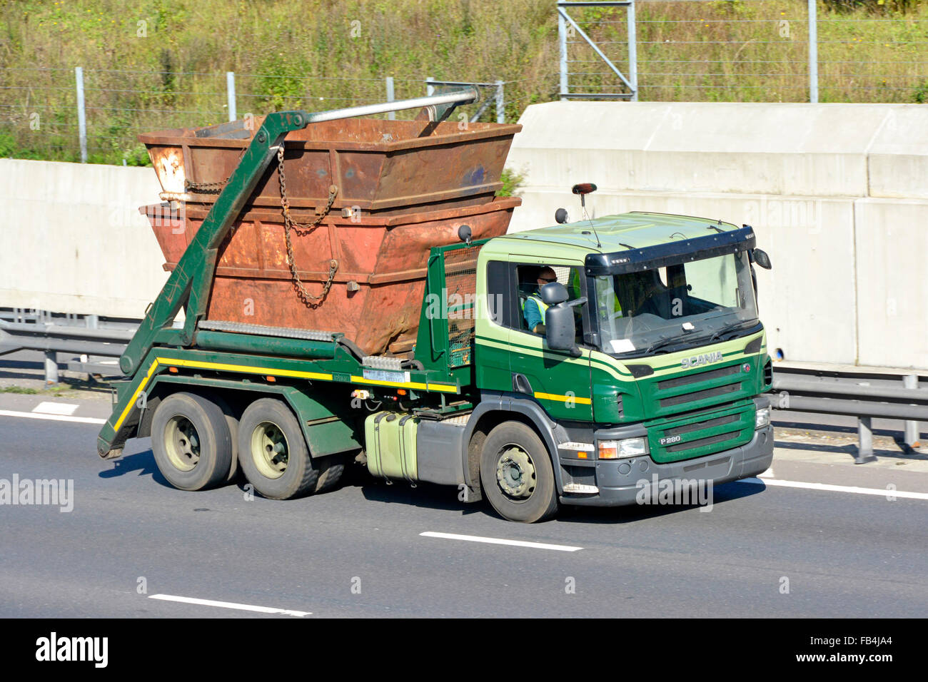 Seitenansicht und Vorderansicht der unmarkierten Doppelachsen-Müllabfuhr überspringt LKW und Fahrer mit nicht markierten mülltonnen, die auf der Autobahn England UK fahren Stockfoto