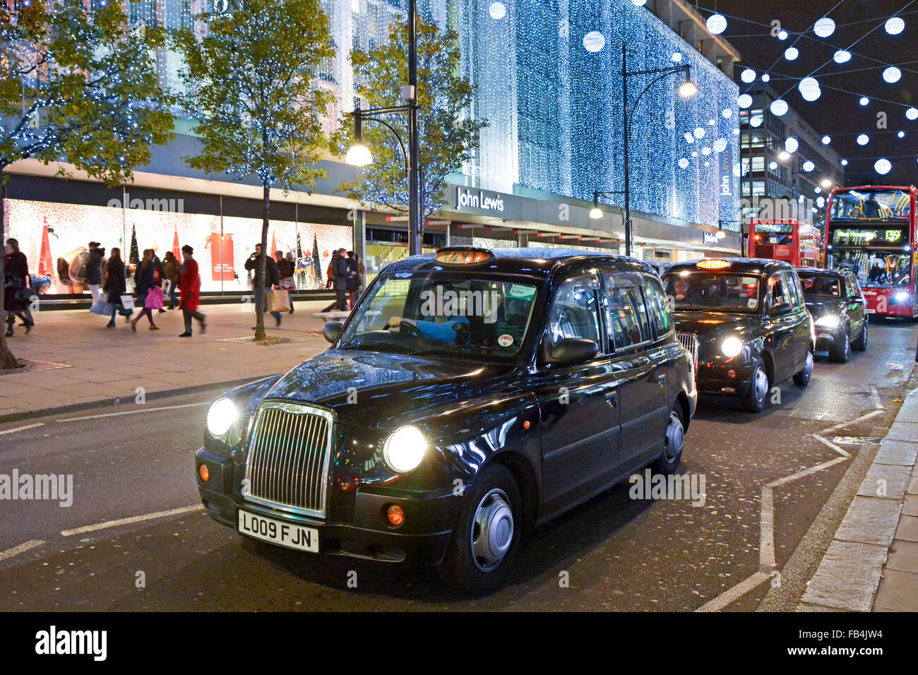 Weihnachtsbeleuchtung Dekoration London Taxifahrer warten in der Verkehrsschlange vor John Lewis Department Store Gebäude in Oxford Street West End UK Stockfoto