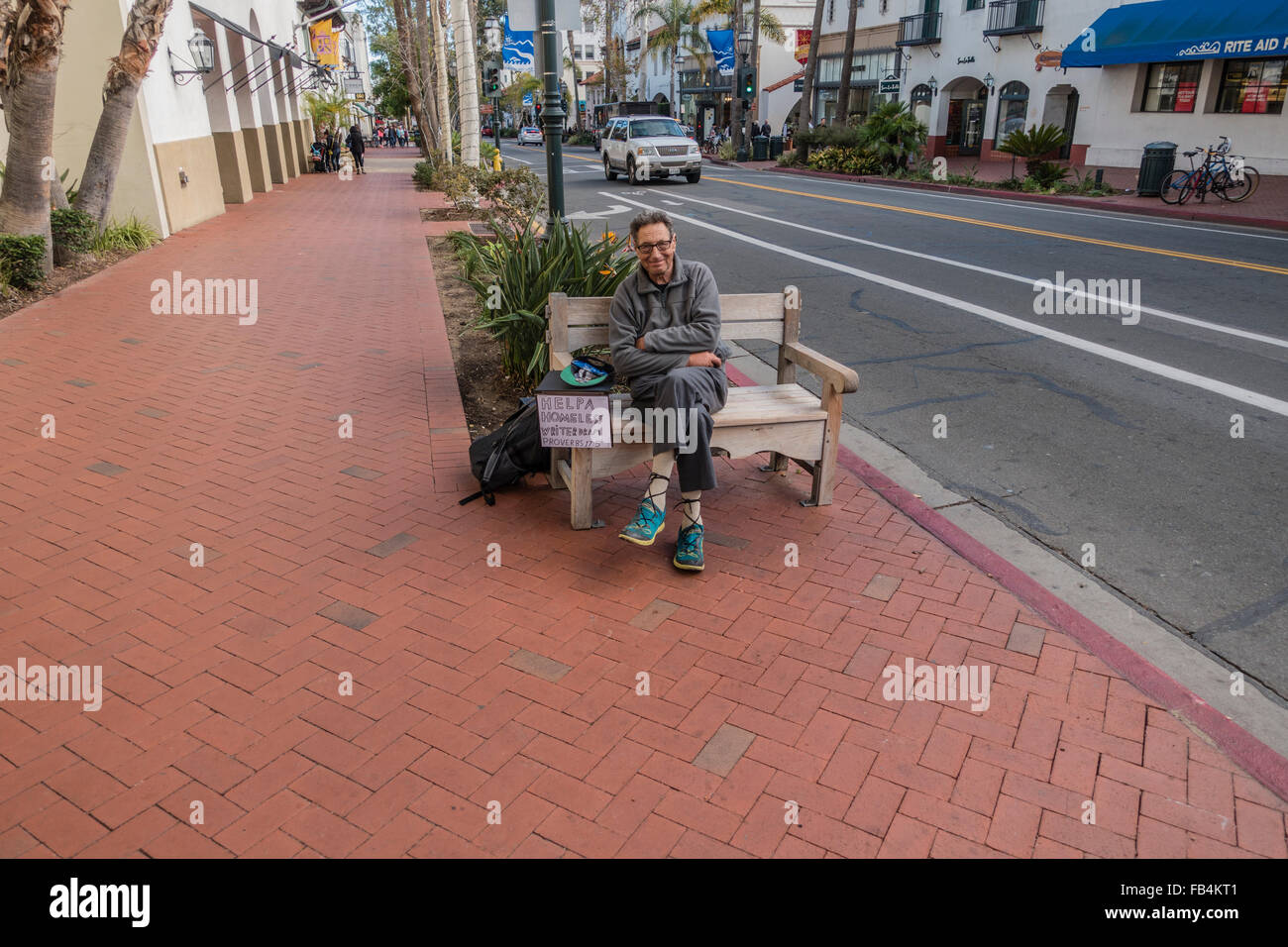 Ein älteren Erwachsenen männlichen Schriftsteller sitzt auf einer Bank am State Street betteln um Geld, die Benutzung eines Zeichens ihn als Obdachlose zu identifizieren. Stockfoto