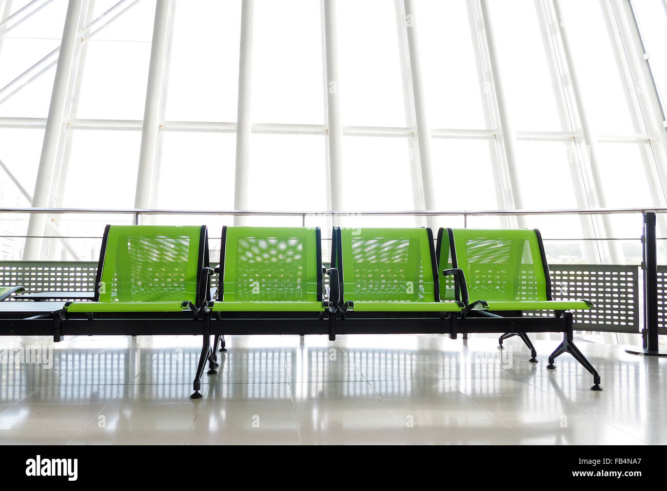 Bank mit grünen Sitze in der Abflughalle eines Flughafens mit riesigen Fenster im Hintergrund. Stockfoto