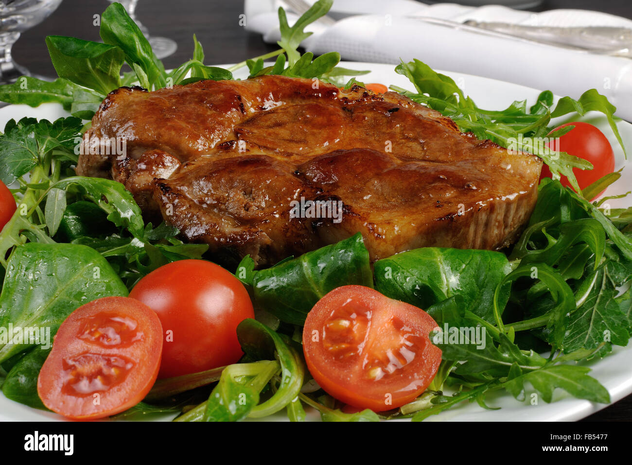 Schweinesteak mit Ketchup, Rucola, Cherry-Tomaten Stockfoto