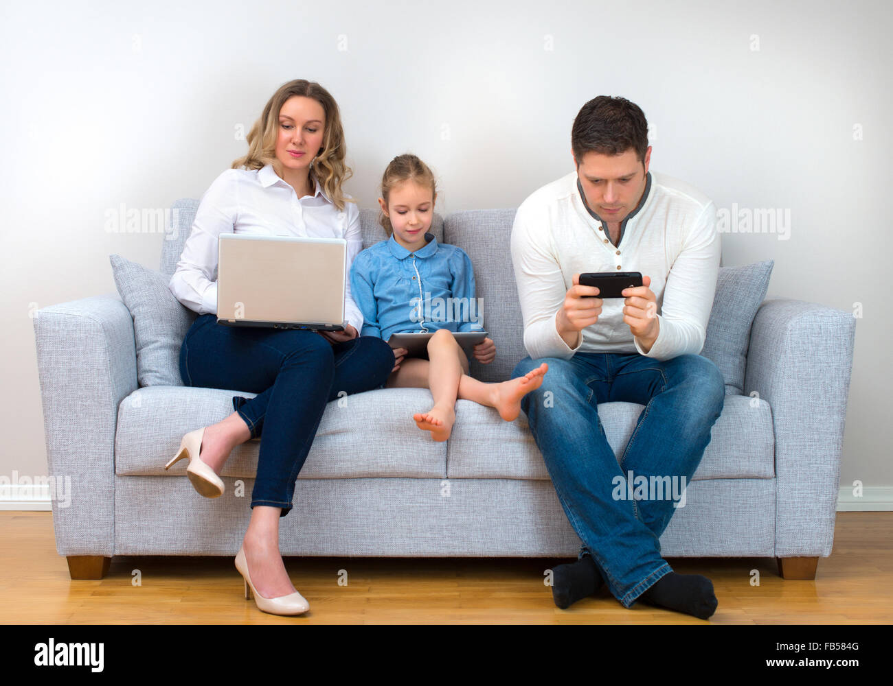 Werte der modernen Familie. Vater, Mutter und Tochter mit elektronischen Geräten. Stockfoto