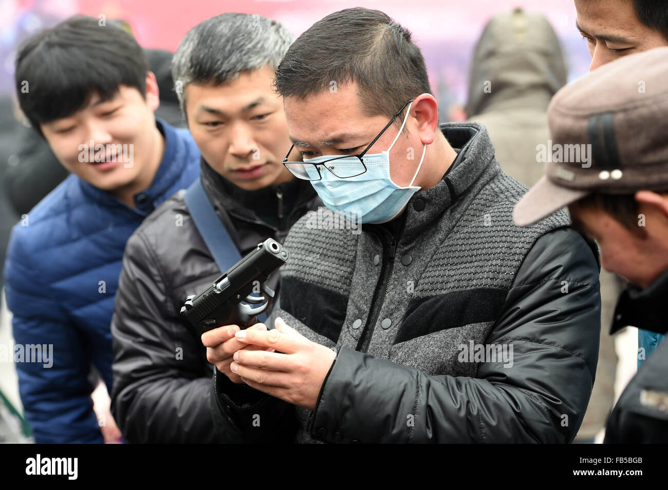 Zhengzhou, China Henan Provinz. 10. Januar 2016. Ein Mann hat einen genauen Blick auf ein Polizei-Waffe auf dem 30. 110 Werbung Tag in Zhengzhou, Zentral-China Henan Provinz, 10. Januar 2016. Menschen in China Anruf 110 für die Polizei zu helfen. Bildnachweis: Li Bo/Xinhua/Alamy Live-Nachrichten Stockfoto