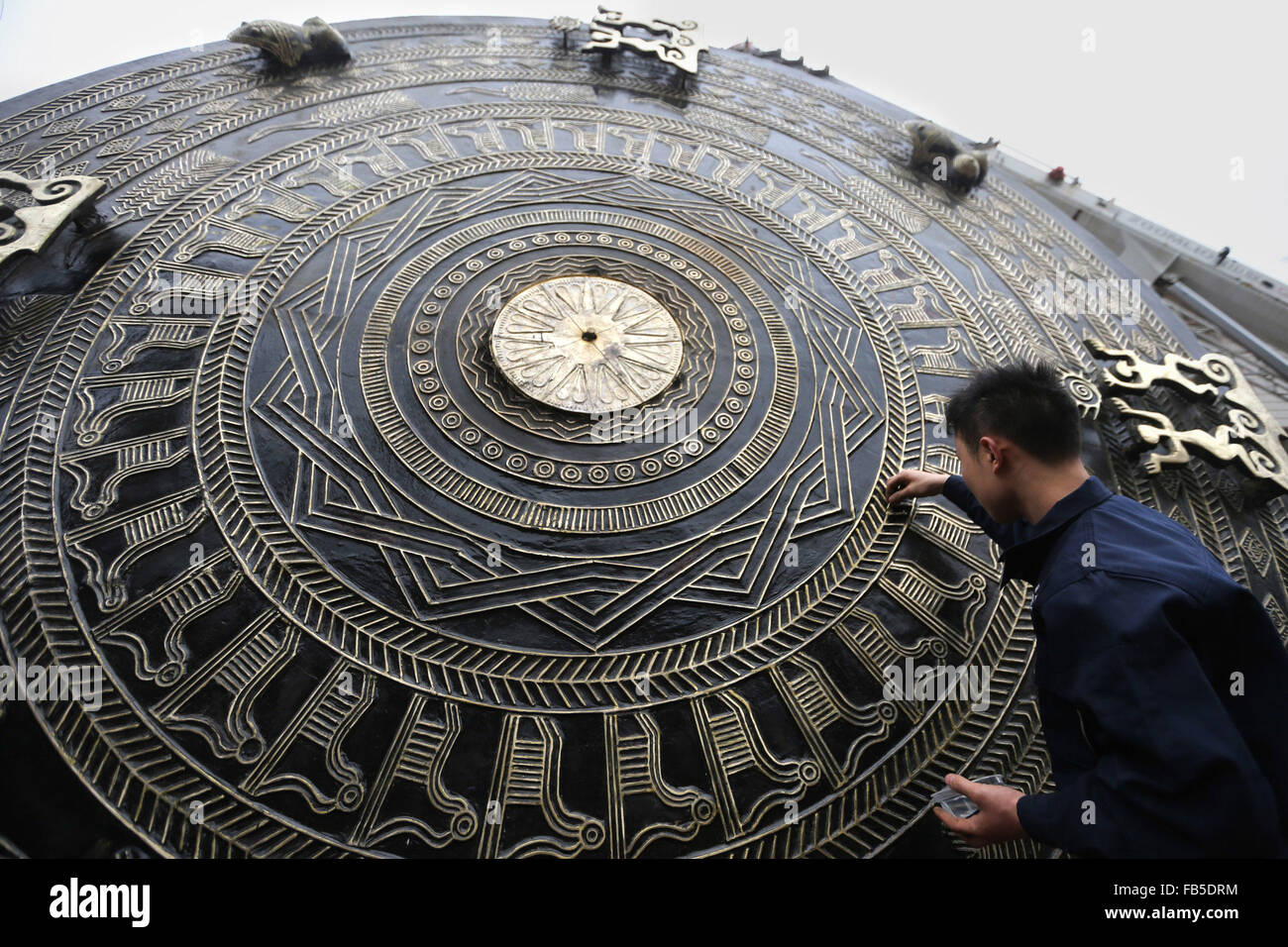 Hechi, Chinas autonomen Region Guangxi Zhuang. 10. Januar 2016. Ein Arbeiter reinigt die Oberfläche der Bronze Trommel in Huanjiang Maonan ethnische autonome Grafschaft, Südwest-China Autonome Region Guangxi Zhuang, 10. Januar 2016. Mit einer Höhe von 2,6 Metern und einen Durchmesser von 4,2 Metern machte die sieben Tonnen schwere Bronze Trommel 20 Personen in einem halben Jahr. © Lu Zengling/Xinhua/Alamy Live-Nachrichten Stockfoto