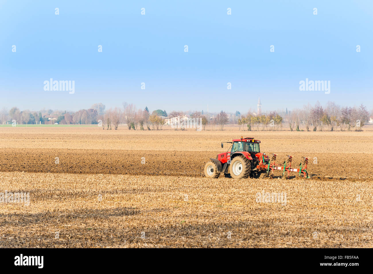 Landwirtschaftliche Arbeit, roter Traktor ein Feld pflügen Stockfoto