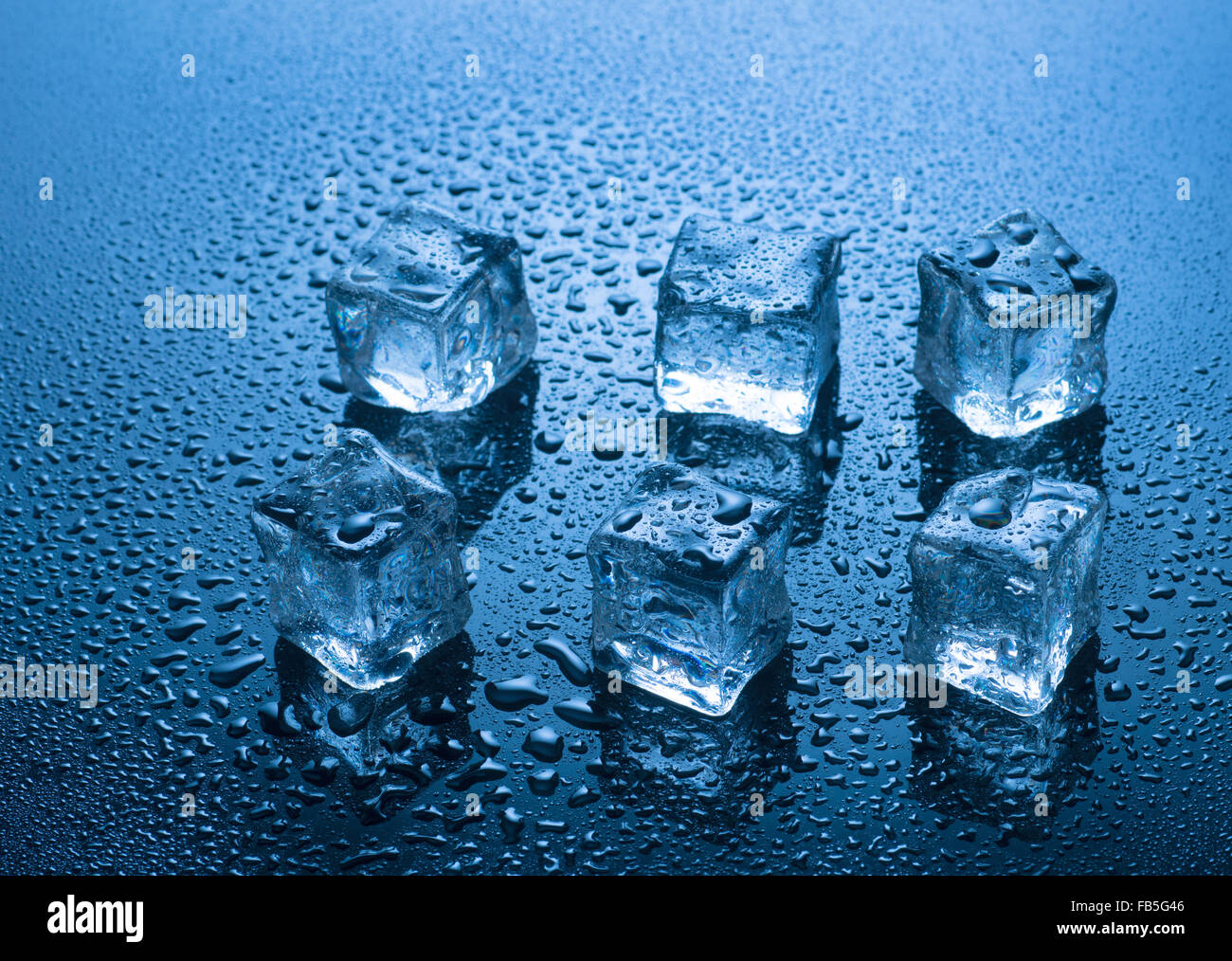 Eiswürfel mit Wasser fällt auf blauem Hintergrund Stockfoto