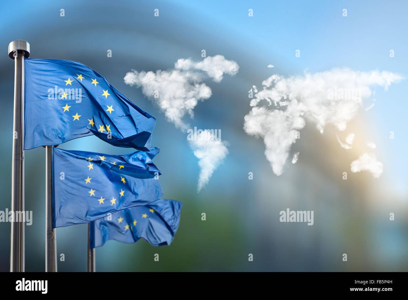 Flaggen der Europäischen Union mit Weltkarte gemacht von Wolken gegen das Europäische Parlament in Brüssel, Belgien Stockfoto