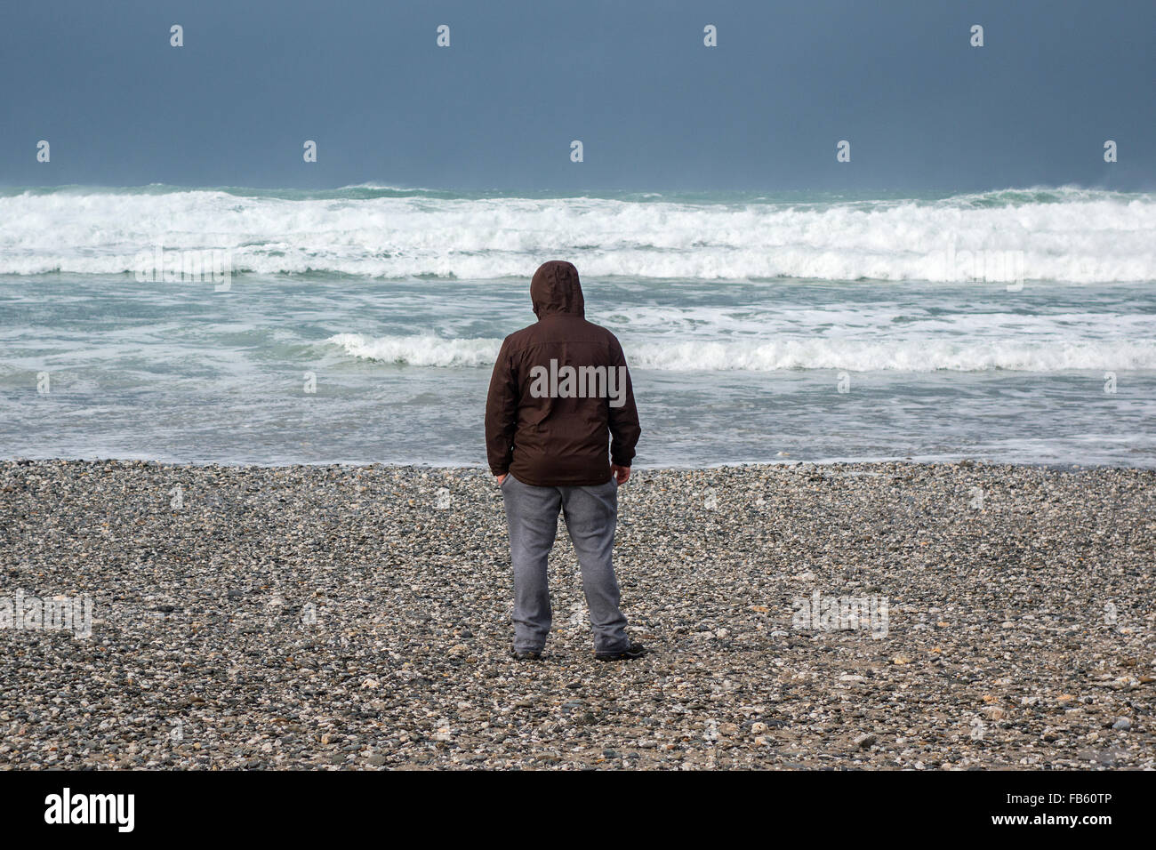 Ein Mann stand an der Küste auf einem Kiesstrand Stockfoto