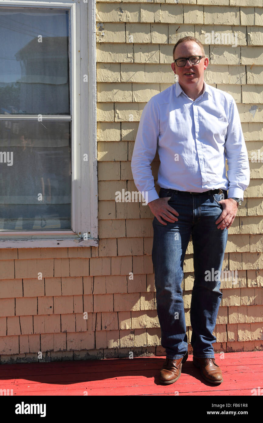 Ein Mann vor einem Haus in Mahone Bay in Nova Scotia, Kanada. Ein Mann steht durch die Fassade. (Modell freigegeben.) Stockfoto