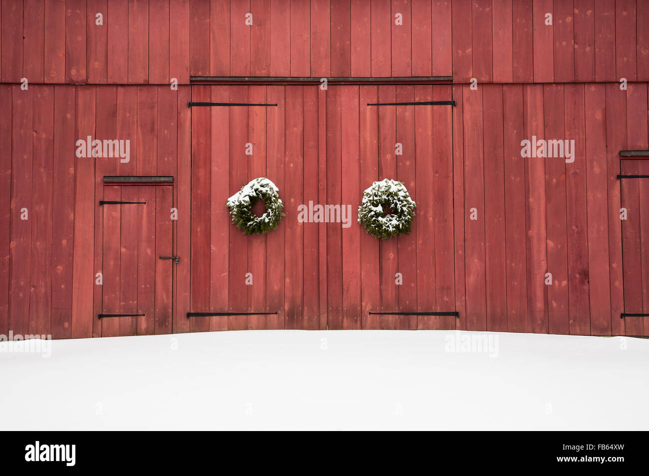 Historische rote Scheunentür Schnee Nahaufnahme kolonialen Weihnachtstür Kränze während Schneesturm in Mercer County, New Jersey, USA, vintage Winterlandschaft Stockfoto