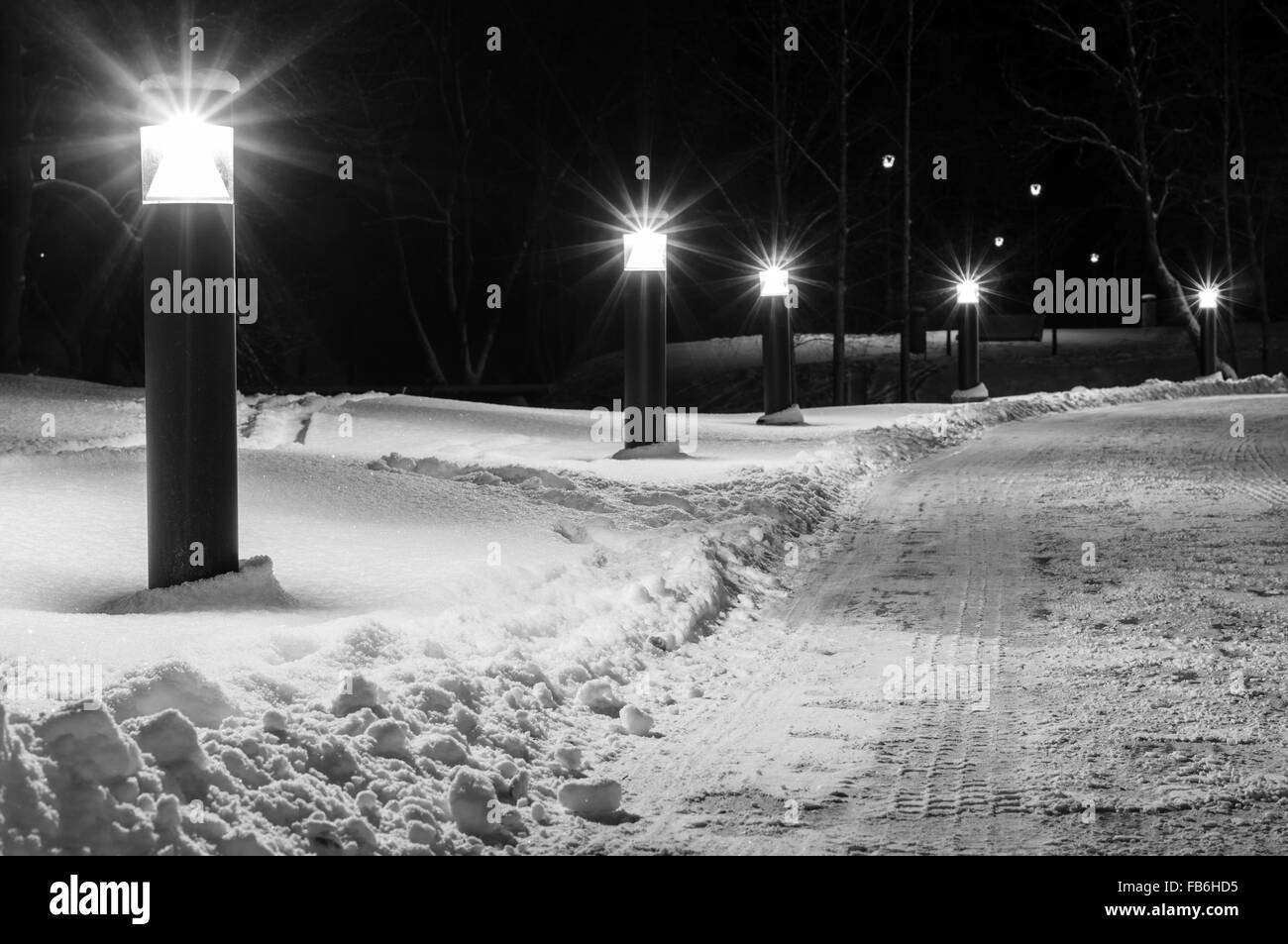 Winterzeit Fußweg beleuchtet durch moderne Laternen, schwarz / weiß Bild Stockfoto