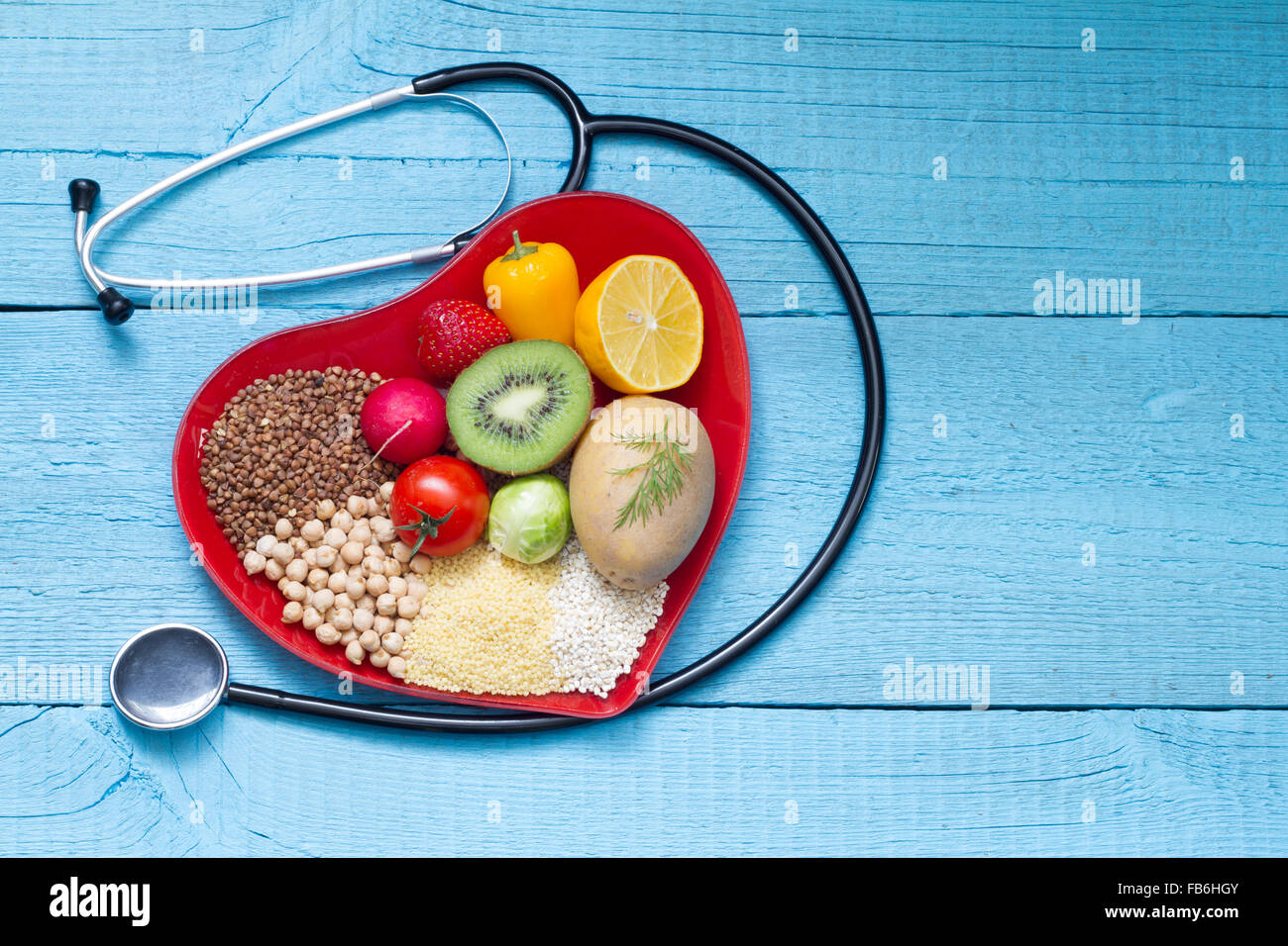 Lebensmittel auf Herz Teller mit Stethoskop Cardiology Konzept auf blauen Tafeln Stockfoto
