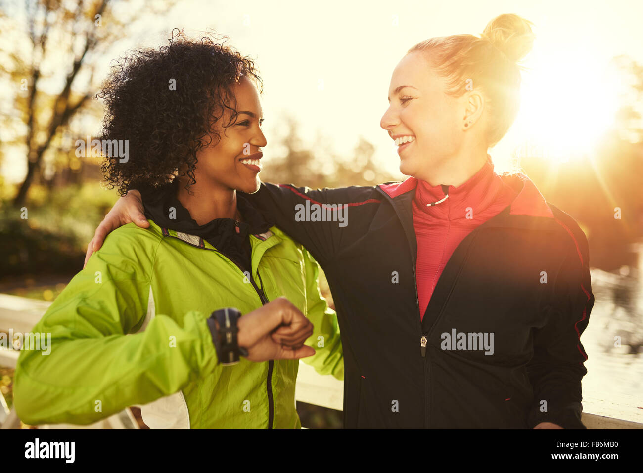 Zwei lächelnde Sportlerinnen umarmt im Freien stehen Stockfoto