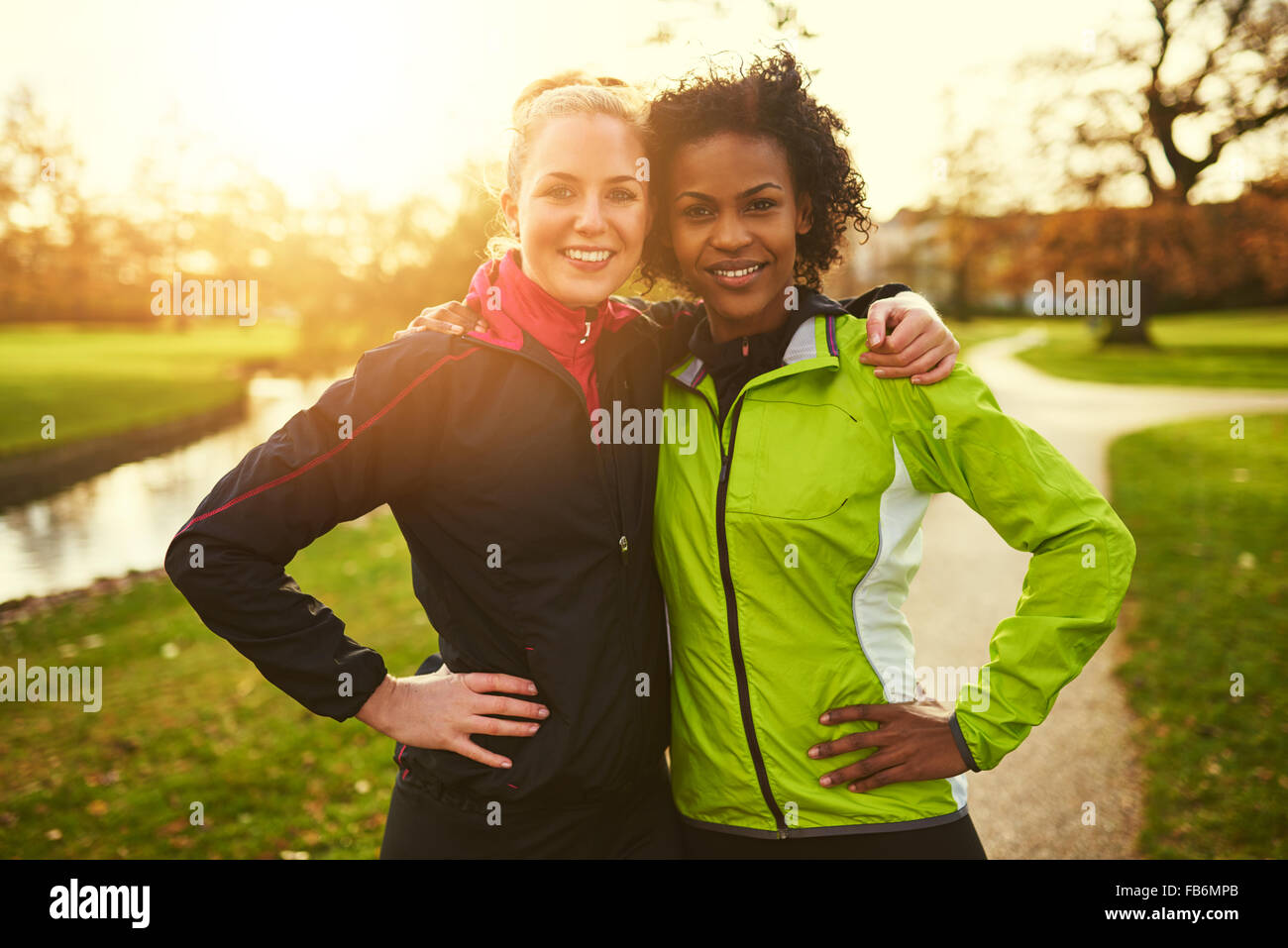 Zwei weibliche Athleten umarmen und auf Kamera, während in PARK-Stellung Stockfoto