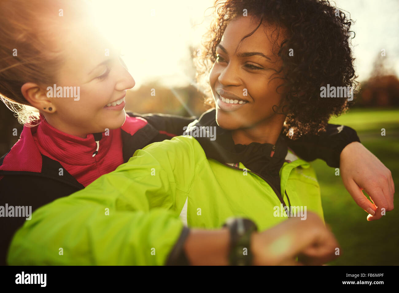 Nahaufnahme von zwei Athletinnen umarmt und lächelnd nach Training im sonnigen park Stockfoto