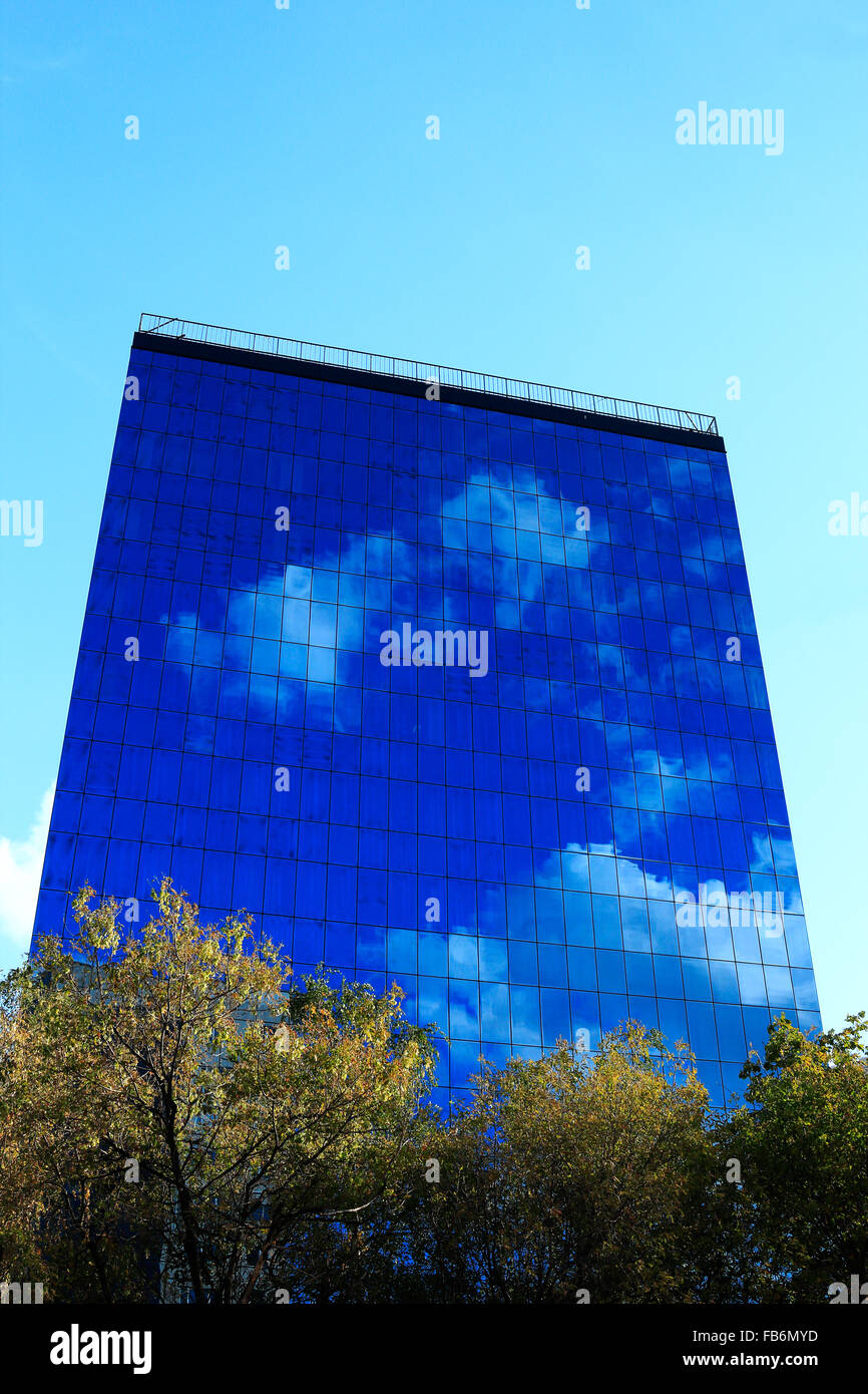 Bürohochhaus mit Reflexion des Himmels und der Wolken an Fassade. Stockfoto
