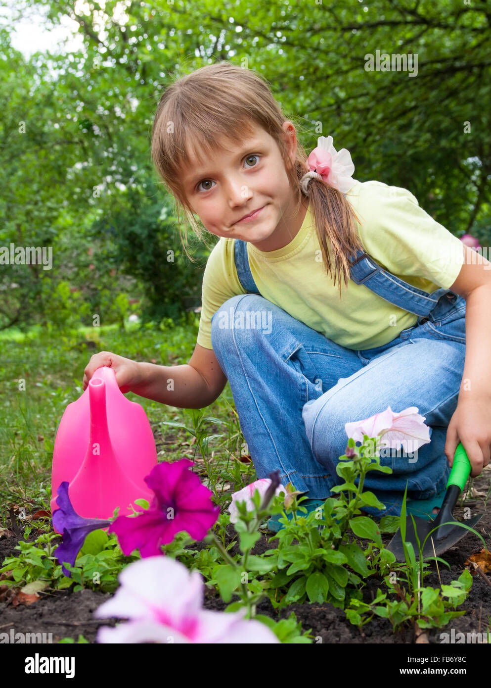 kleines Mädchen in die Federarbeit helfen im Garten Stockfoto