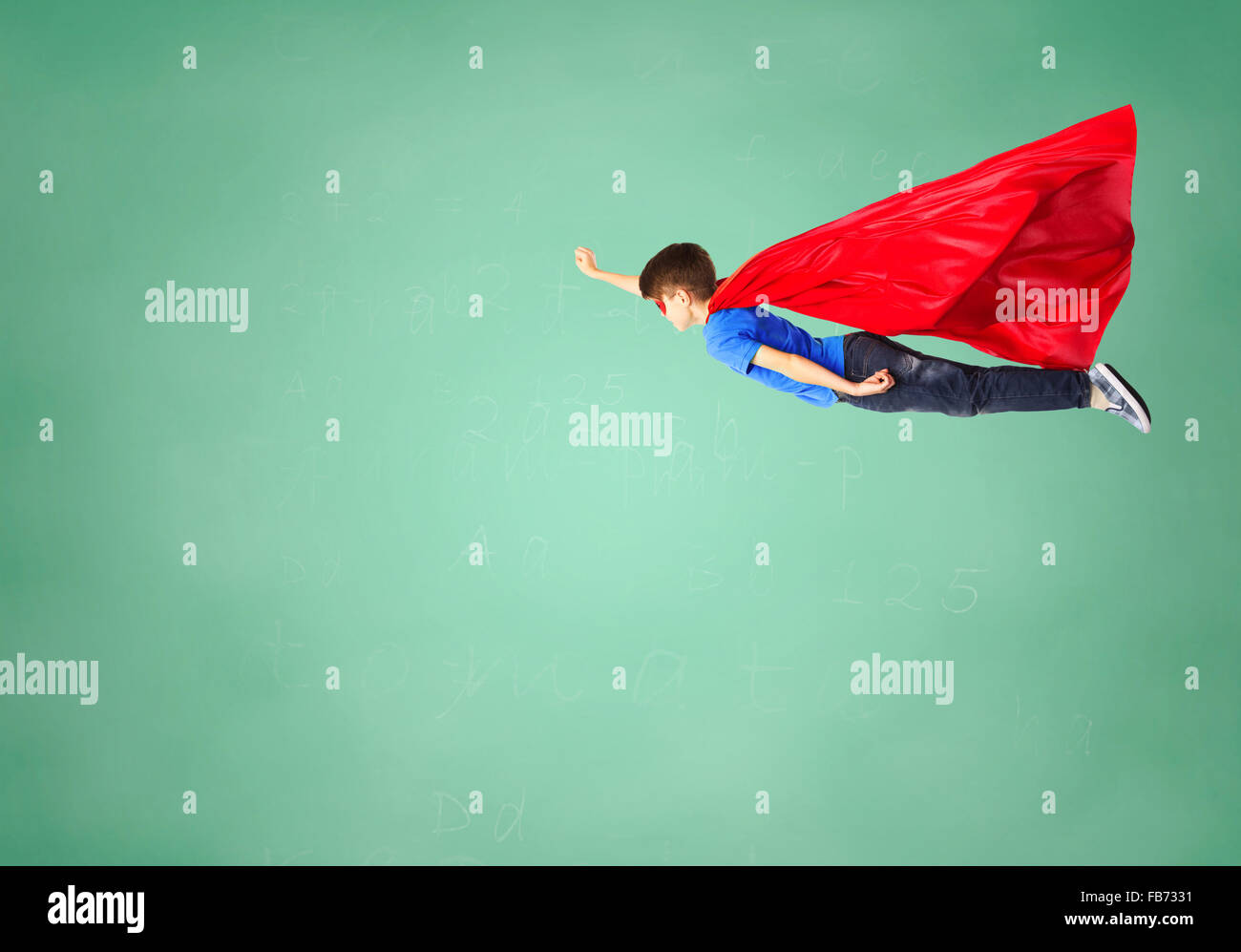 Junge im roten Superhelden Cape und Maske, die fliegen in der Luft Stockfoto