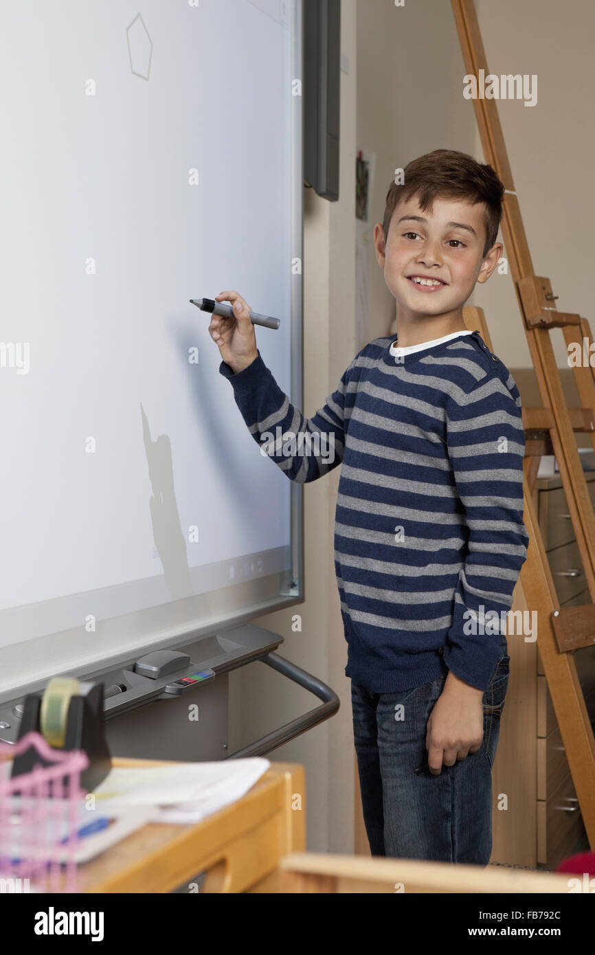 Junge Zeichnung auf Leinwand im Klassenzimmer, wegschauen Stockfoto