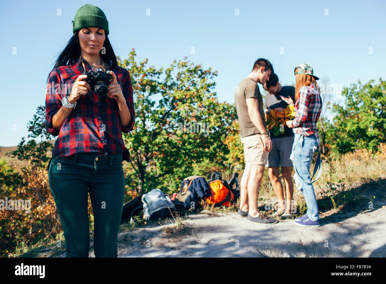 Junge Frau betrachten Fotos vor der Kamera mit Freunden im Wald stehen Stockfoto