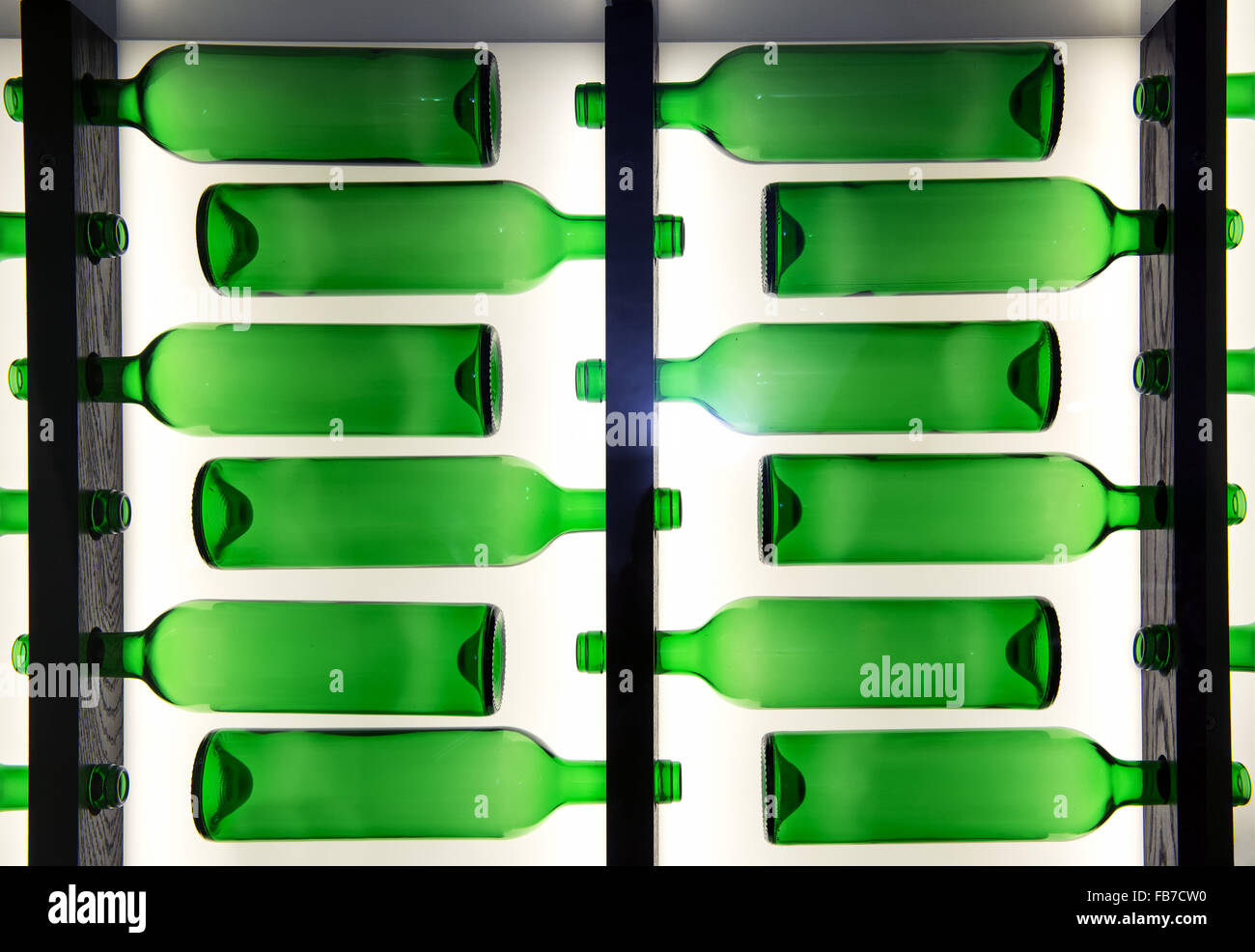 Dekorative Muster der grüne Glasflaschen angeordnet in Reihen gegenüber in wechselnden Richtungen mit Hintergrundbeleuchtung Stockfoto