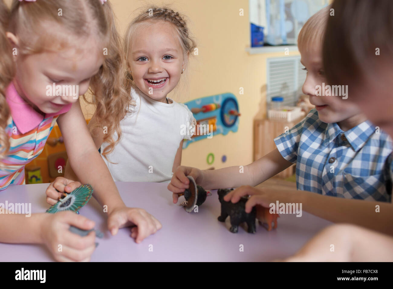 Porträt von fröhliches Mädchen mit Freunden spielen mit Spielzeugtiere am Tisch im Klassenzimmer Stockfoto