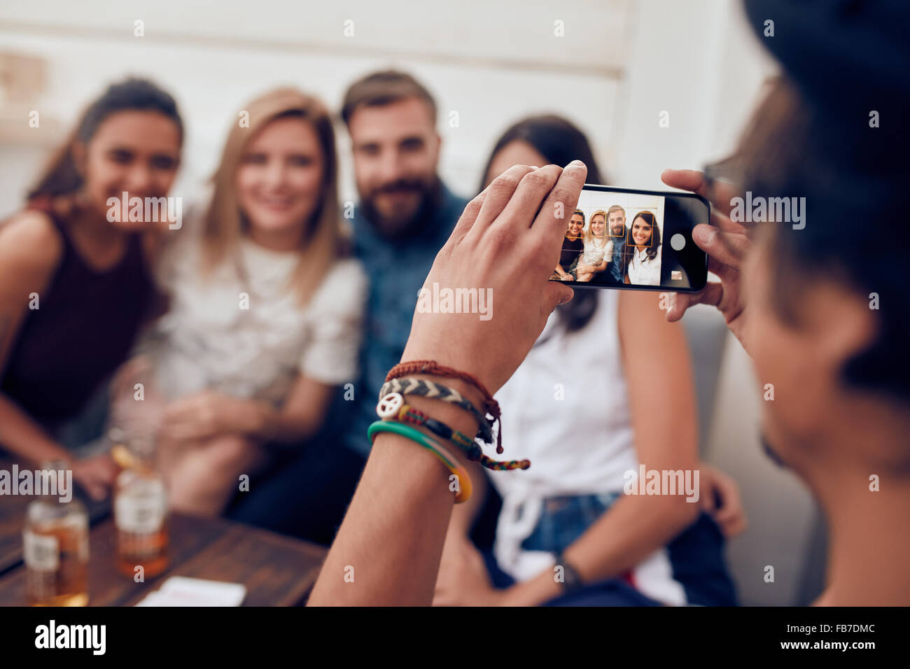 Menschen nehmen Foto seiner Freunde mit Handy. Junge Menschen sitzen zusammen auf einer Party genießen. Stockfoto