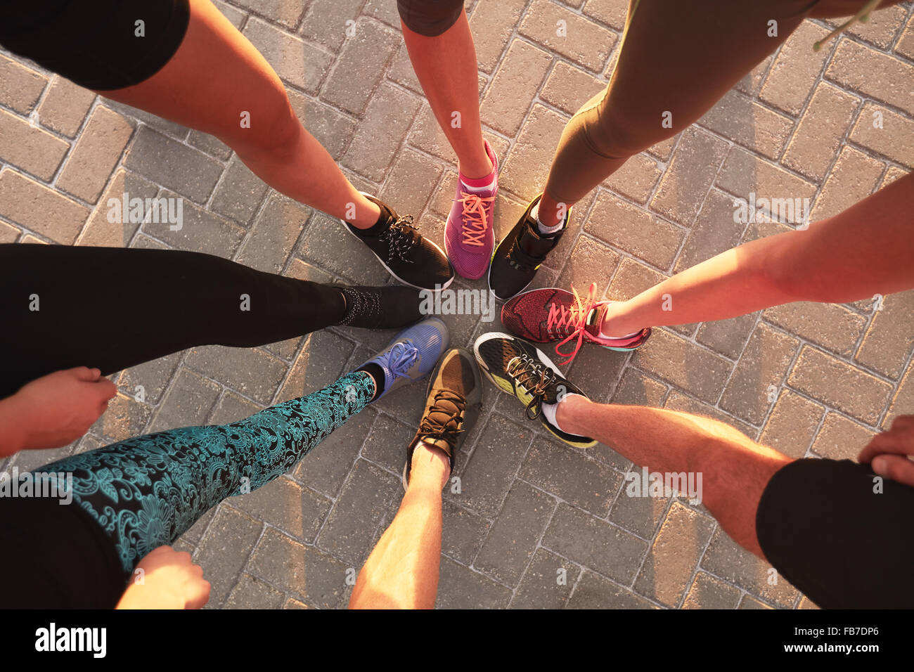 Beine der Athleten tragen Sportschuhe in einem Kreis. Draufsicht der Läufer zusammenstehen. Stockfoto
