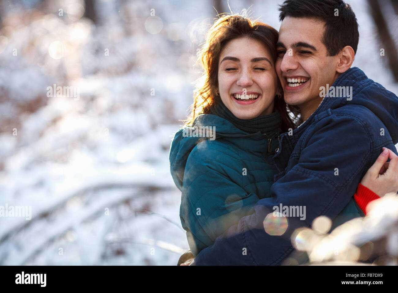 Fröhliches junges Paar umarmt auf Feld im winter Stockfoto