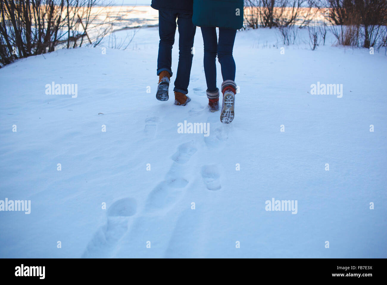 Geringen Teil junges Paar zu Fuß auf schneebedeckten Feld Stockfoto