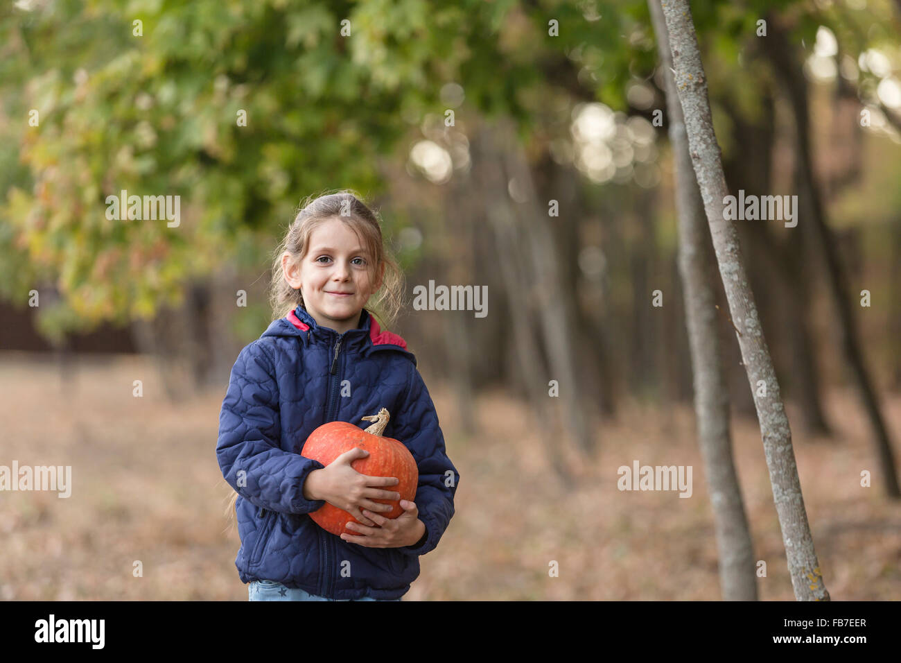 Porträt von lächelnden Mädchen Holding Kürbis im Wald Stockfoto