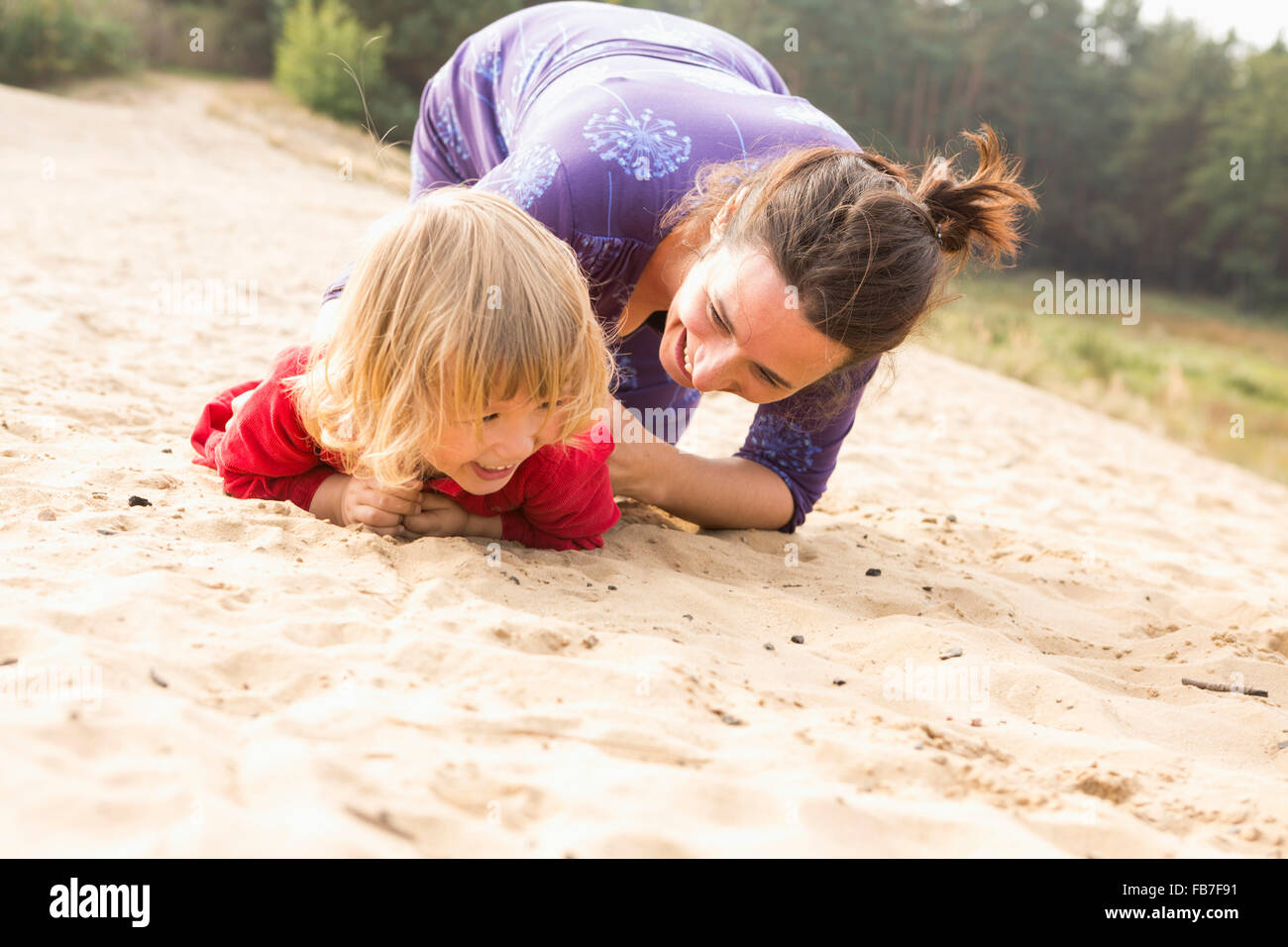 Glückliche Mutter mit Tochter auf Sand spielen Stockfoto