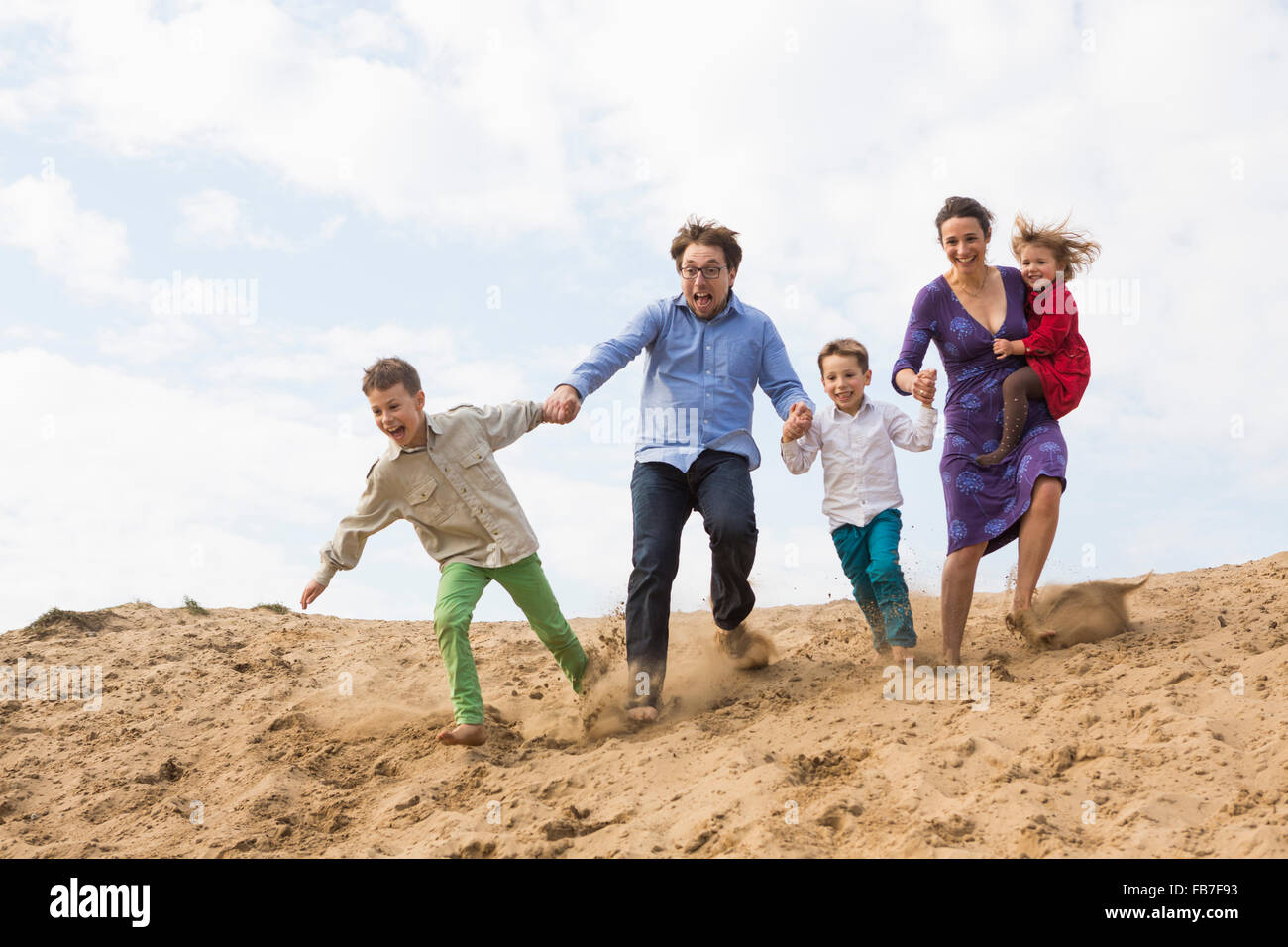 Familie Hand in Hand und genießen Sie auf Sanddüne gegen Himmel Stockfoto