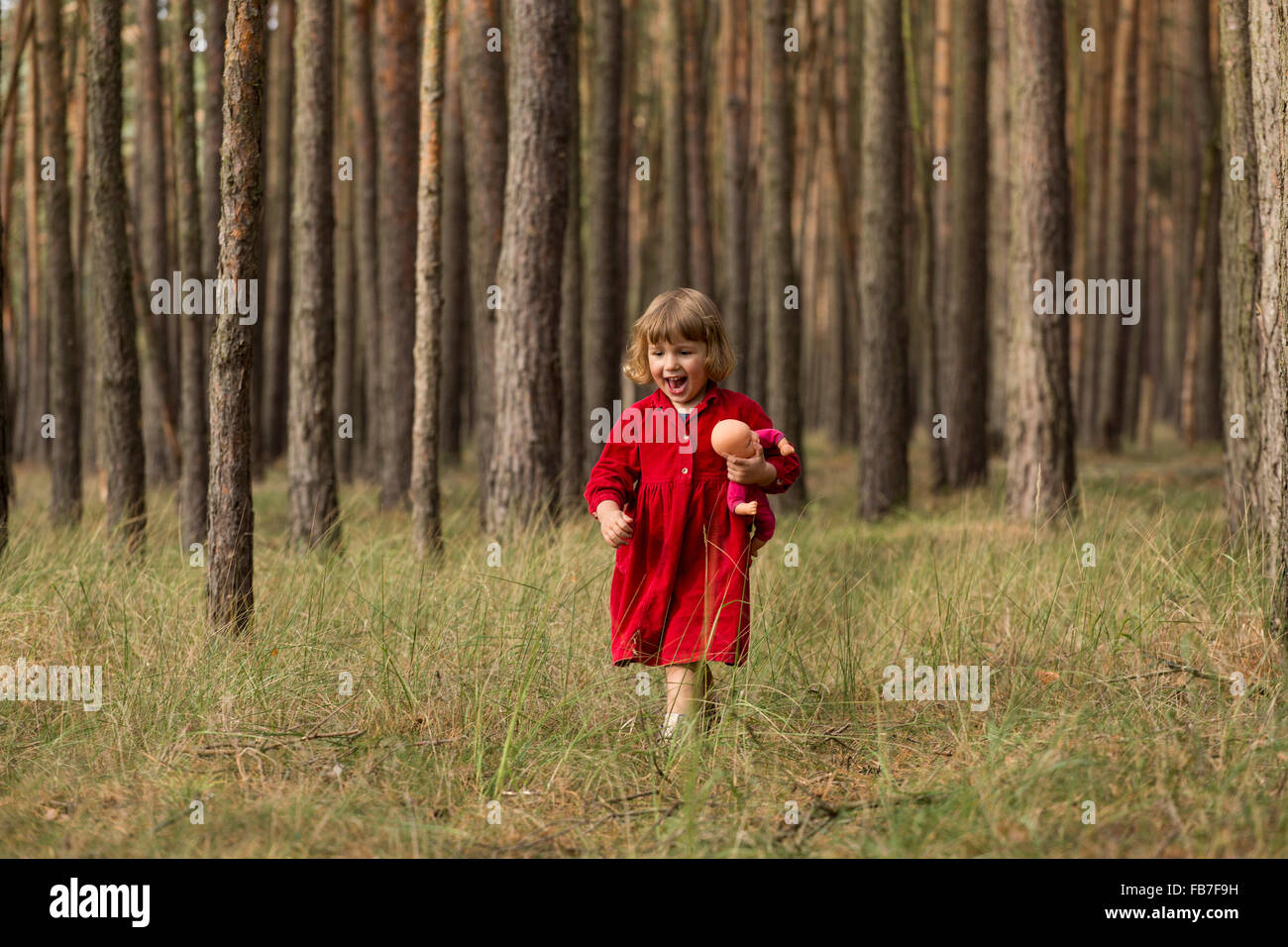 Glückliches Mädchen Holding Puppe bei einem Spaziergang im Wald Stockfoto