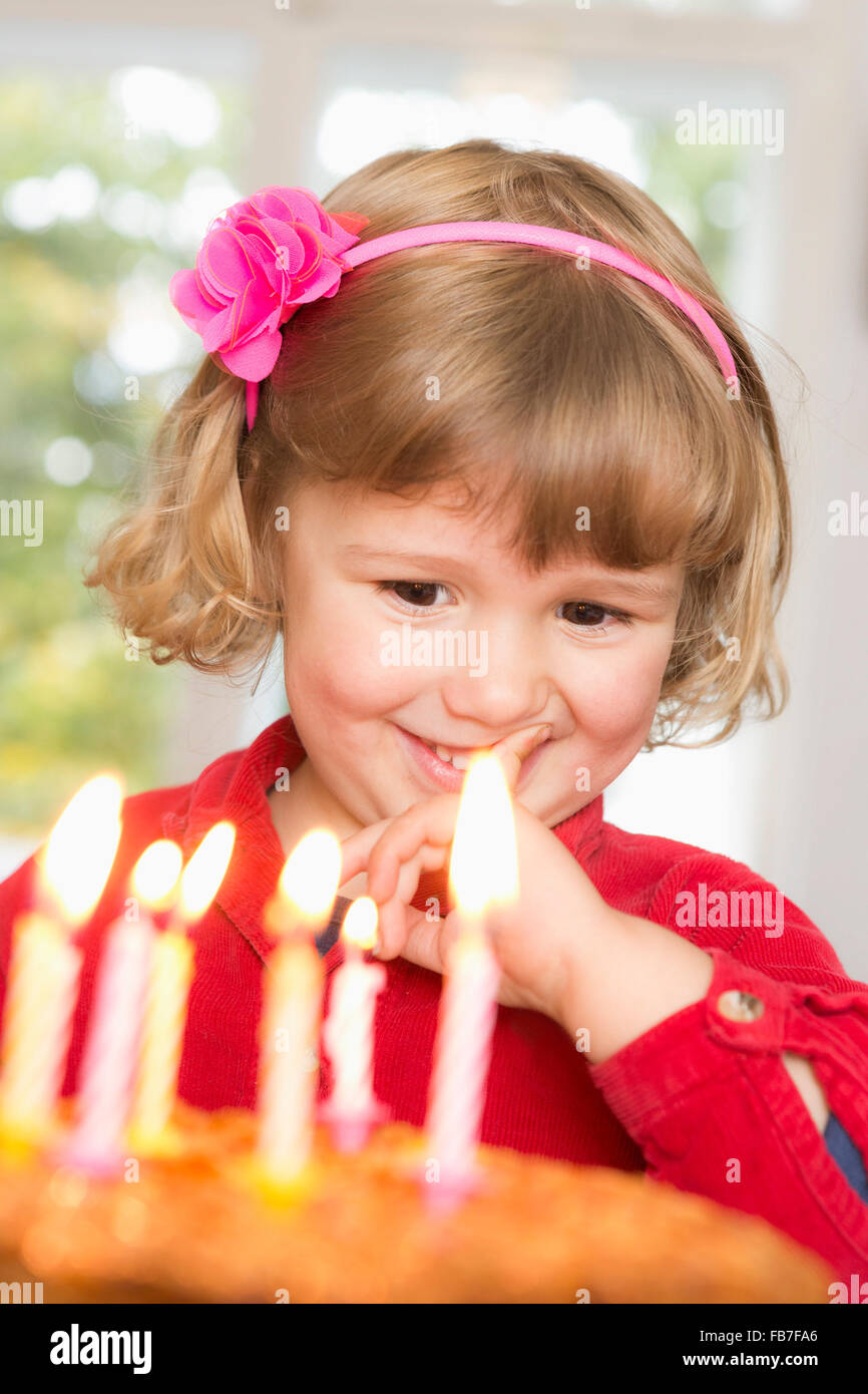 Niedliche Mädchen Blick auf Geburtstagskuchen Stockfoto