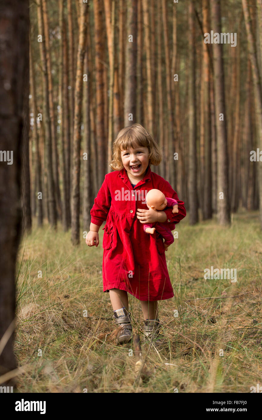 Glückliches Mädchen Holding Puppe bei einem Spaziergang im Wald Stockfoto