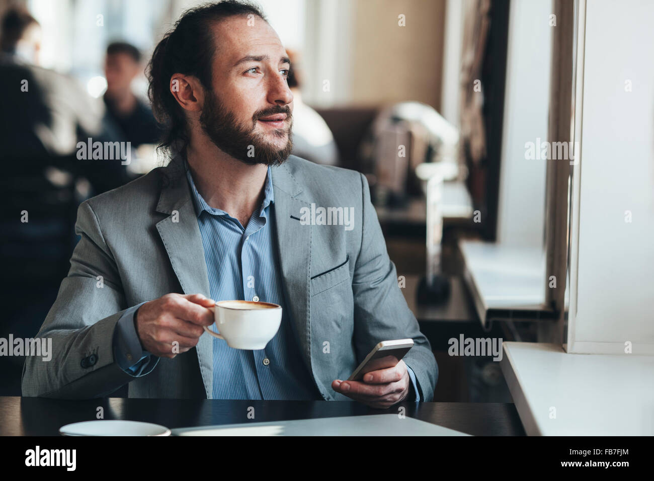 Kaffeetasse und Handy hält in Café Mitte adult Geschäftsmann Stockfoto