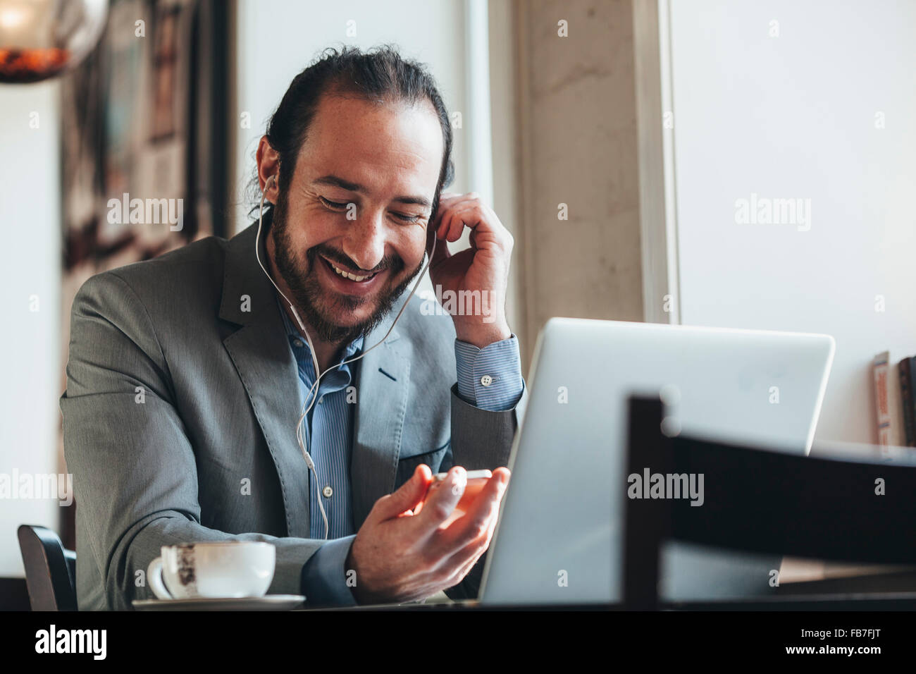 Glücklich Mitte adult Geschäftsmann Musik hören über Mobiltelefon im café Stockfoto
