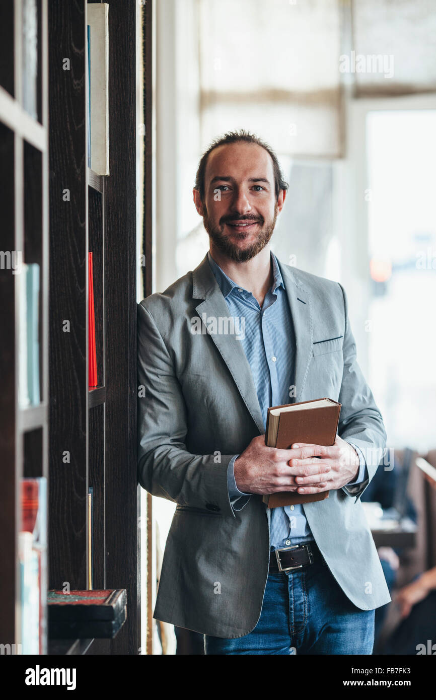 Porträt von Mitte adult Geschäftsmann Betrieb Buch im Café glücklich Stockfoto