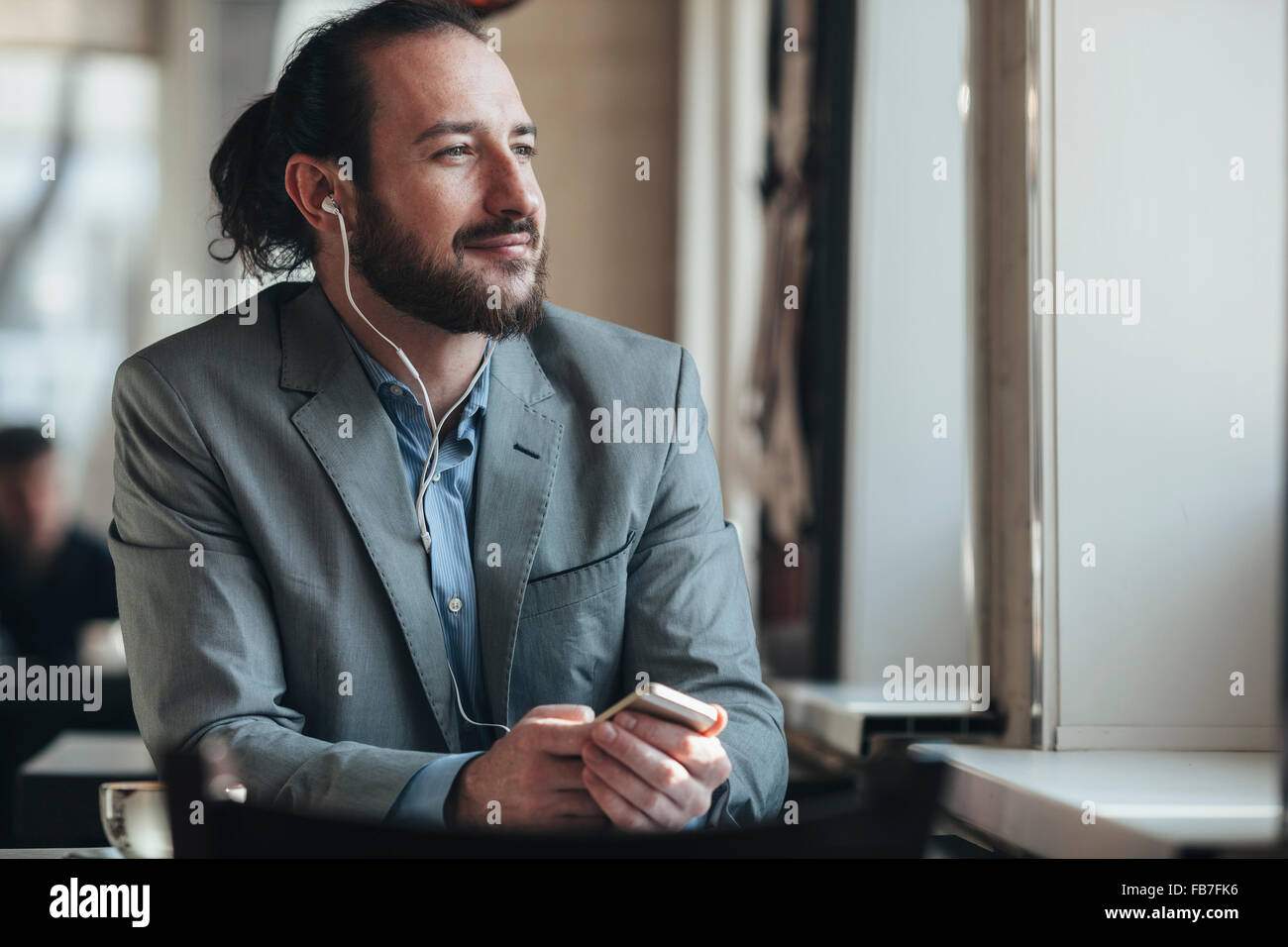 Nachdenklich Geschäftsmann Musik hören über Mobiltelefon im café Stockfoto