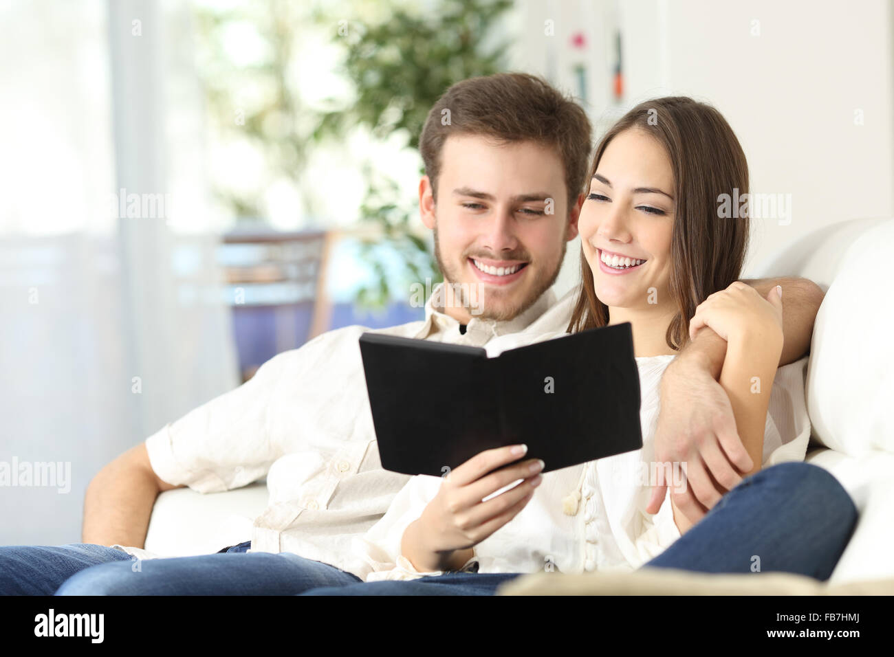 Paar zusammen einen Leseleitfaden in ein Ebook auf einer Couch zu Hause sitzend Stockfoto