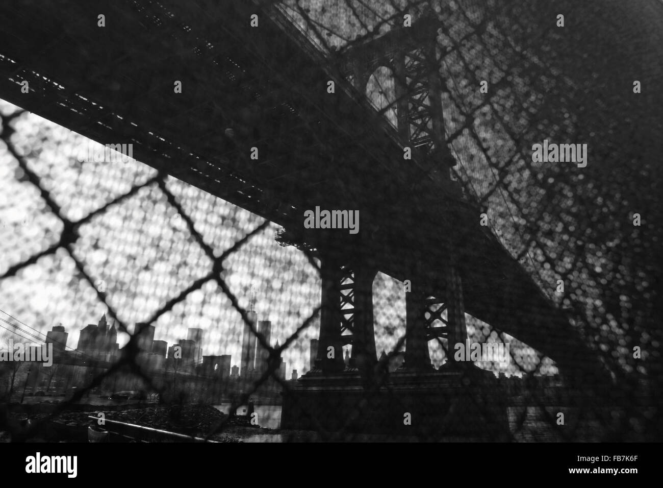 Verzerrte Sicht der Manhattan Bridge Waterfront New York City durch einen Drahtzaun Sicherheit Industrie. Monochrom, schwarz / weiß Bild. Stockfoto