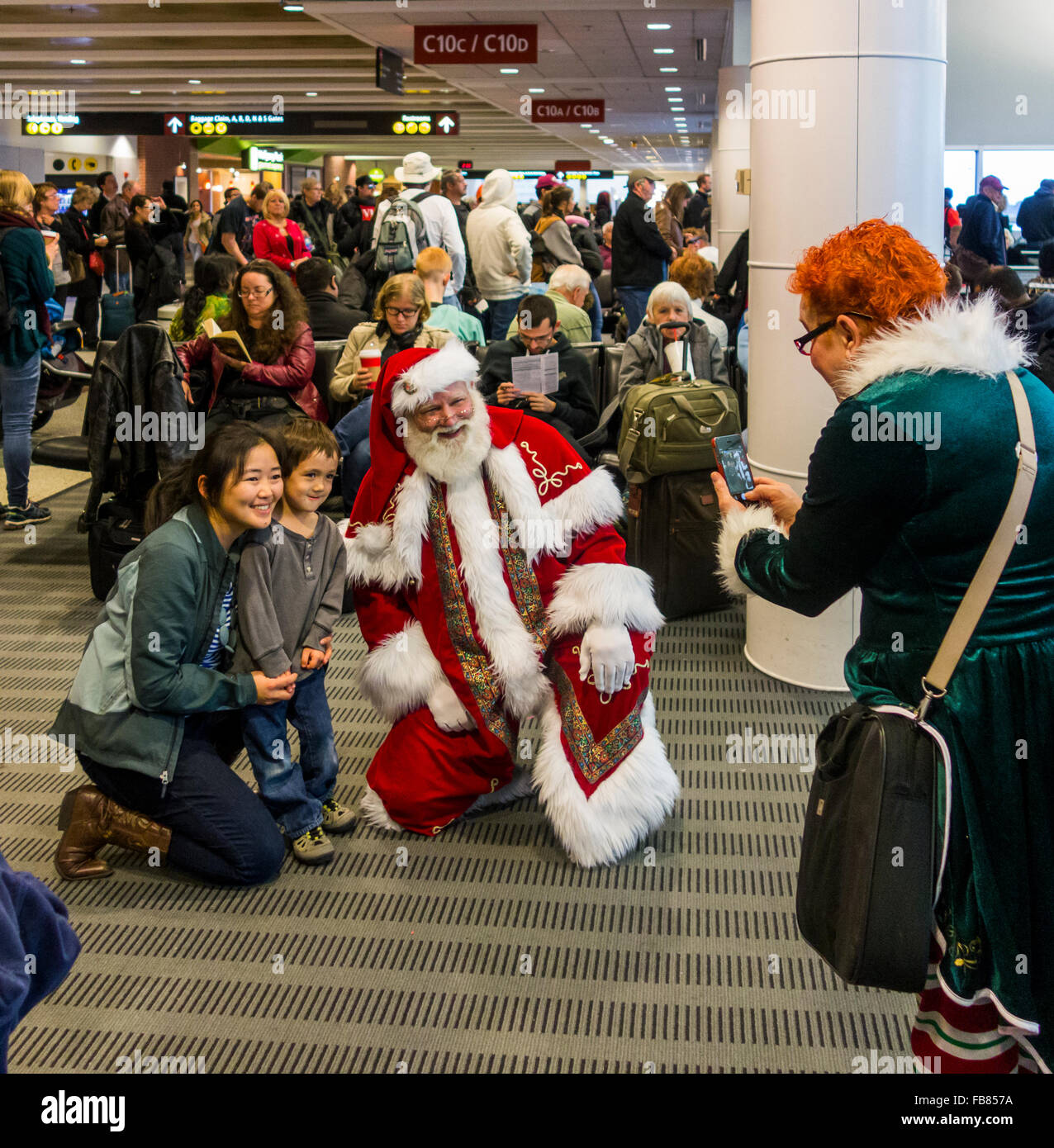 Mann verkleidet als Weihnachtsmann posiert mit Kindern am SeaTac Flughafen, Washington State, USA Stockfoto