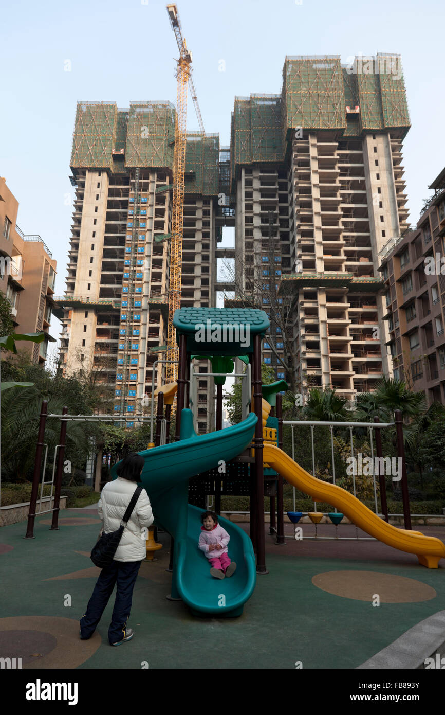 Ein Kleinkind spielt auf dem Spielplatz von einer gated Community, während der Komplex der Wohnungen weiterhin mit Highrise Wohn zu erweitern Stockfoto
