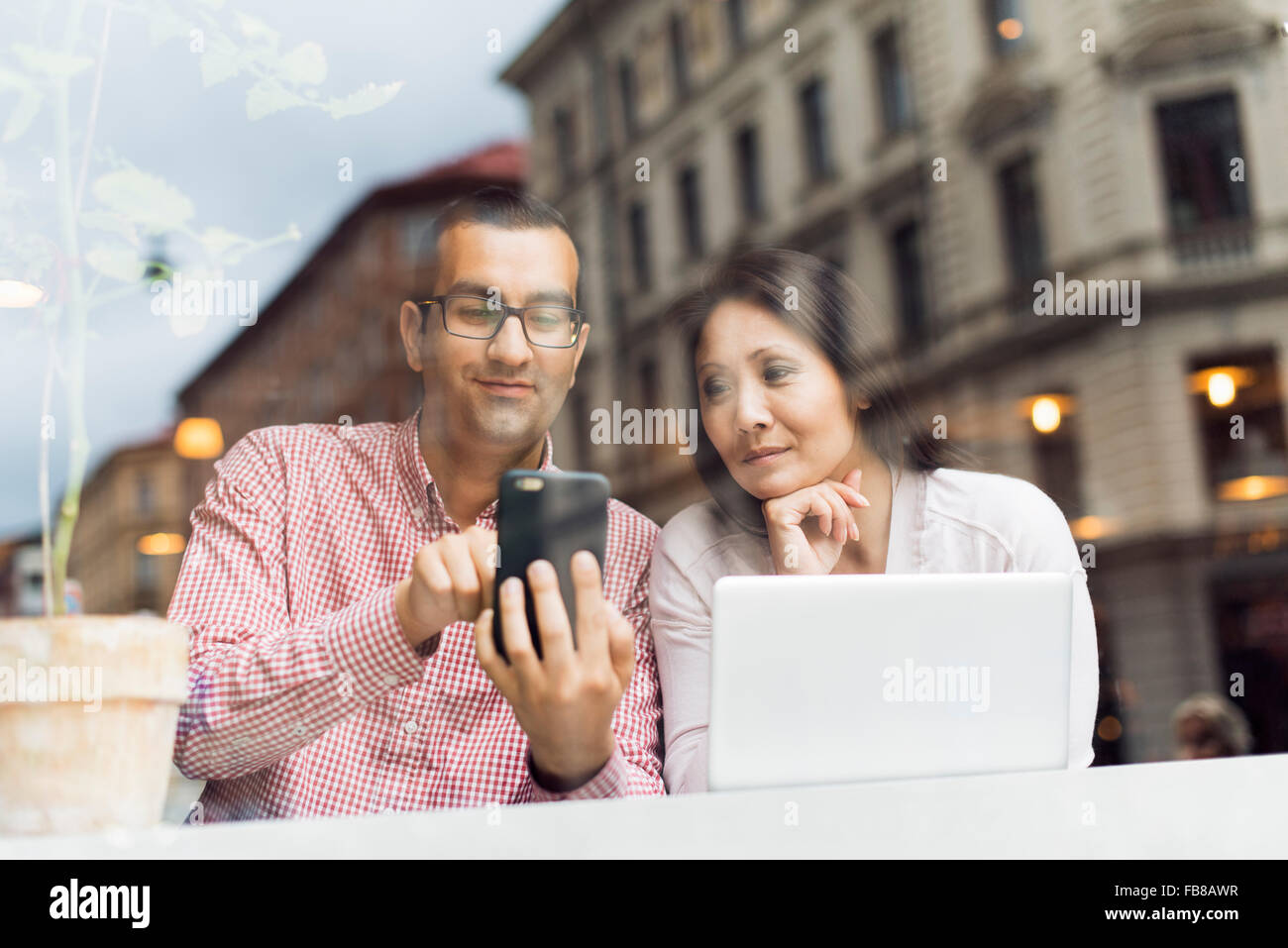Schweden, Uppland, Stockholm, Mann und Frau mit Smartphone im café Stockfoto
