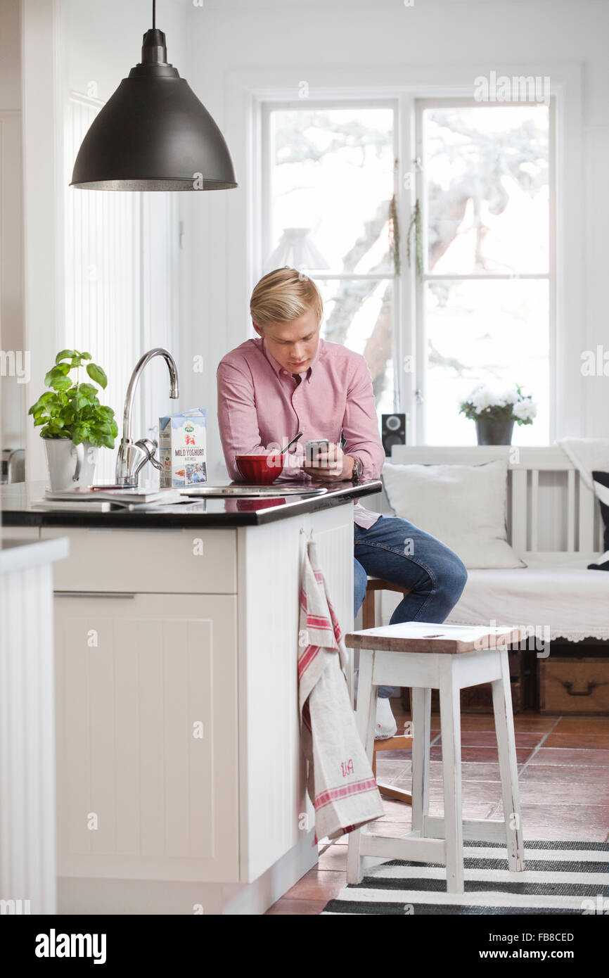 Schweden, Teenage Boy (16-17) SMS in Küche Stockfoto