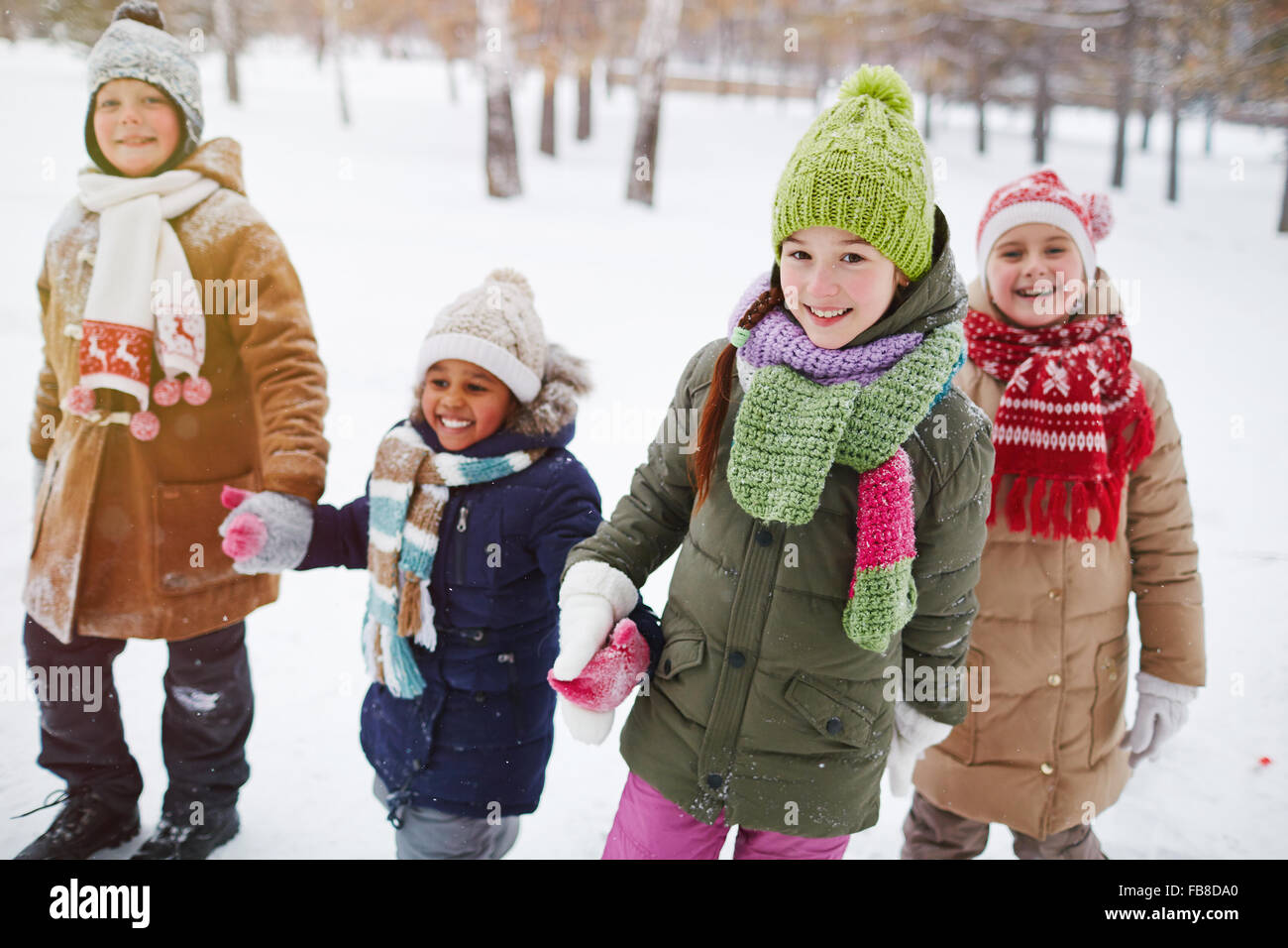 Gruppe von freundlichen Mädchen und jungen in Winterbekleidung Einnahme Spaziergang im Schnee Stockfoto