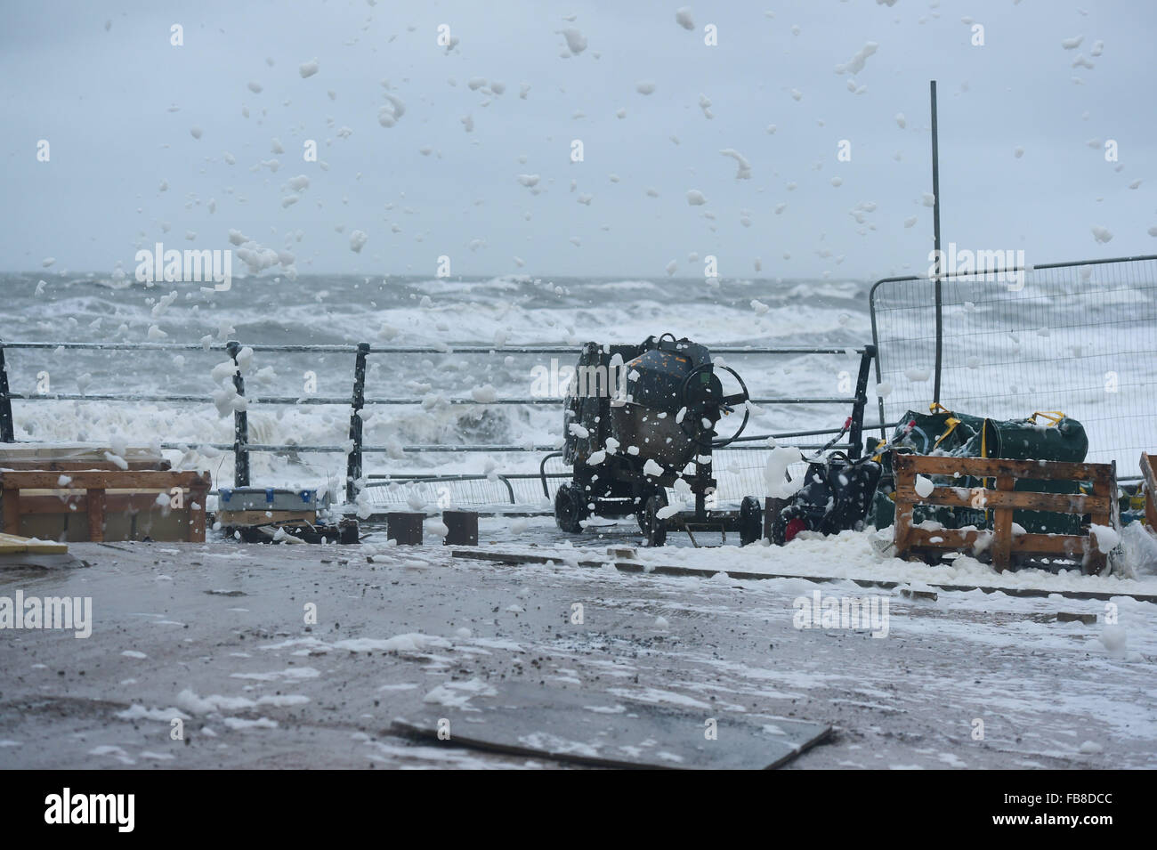 Aberystwyth Wales UK, Montag, 12. Januar 2015 UK Wetter Gale zwingen Winde und 5 m hohen Gezeiten am 09:15 zu kombinieren, um Ströme von Meer weht Schaum Tube zu bringen, wie Schnee Schneestürme über die Strandpromenade in Aberystwyth an der Cardigan Bay Küste im Westen von Wales UK Foto-Credit: Keith Morris/Alamy Live News Stockfoto