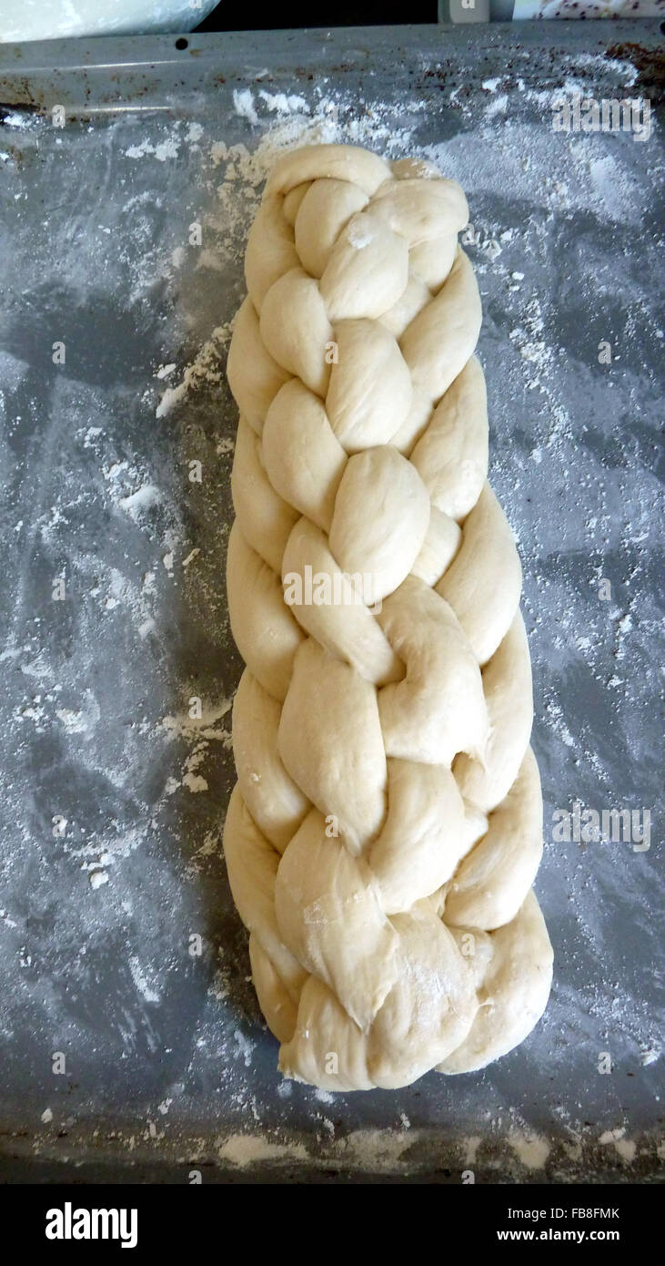Ungebrannten acht-Strang geflochten Laib Brot auf einem bemehlten Backblech Stockfoto